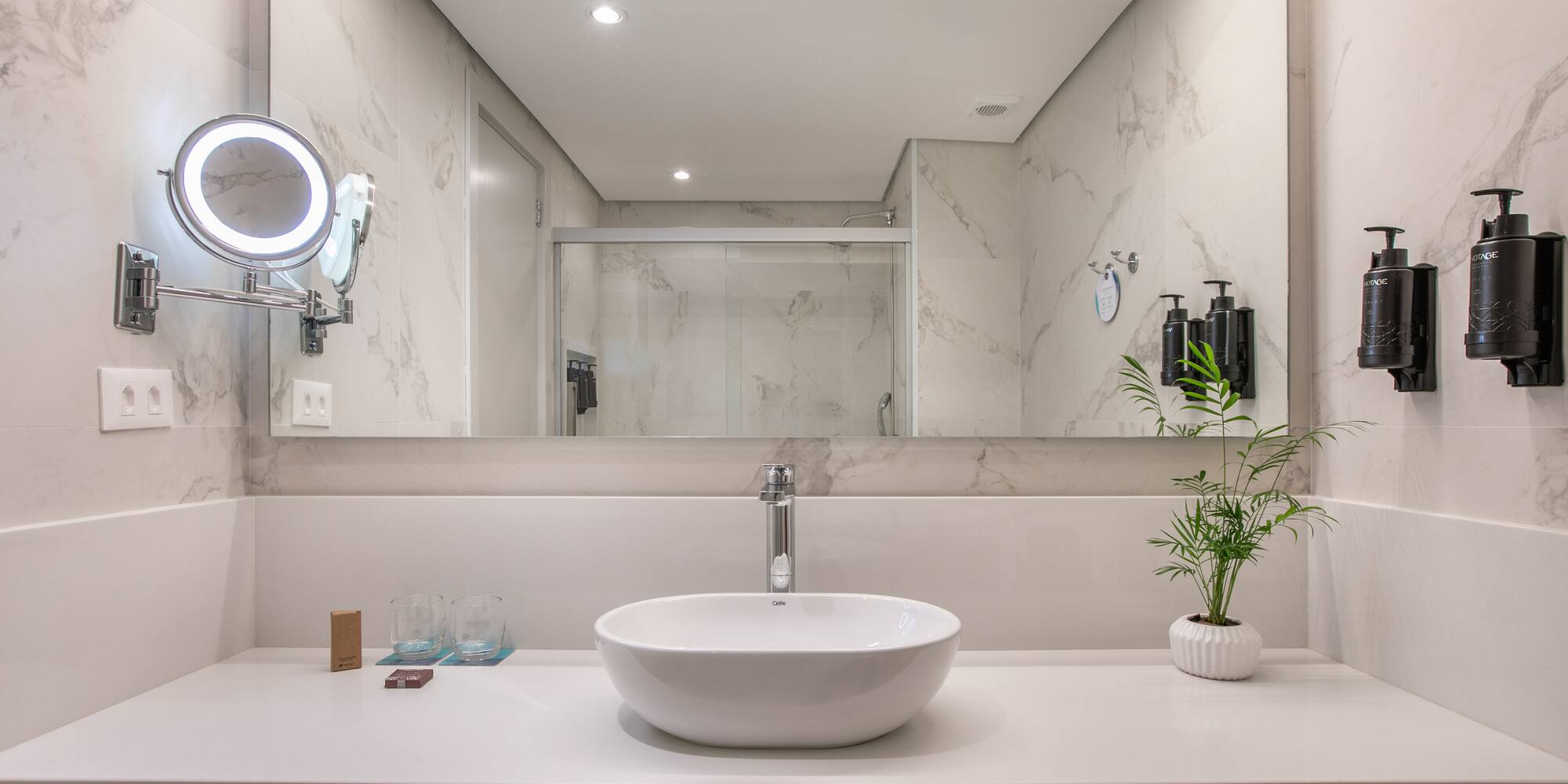 Modern bathroom vanity with vessel sink, large mirror, and marble walls.
