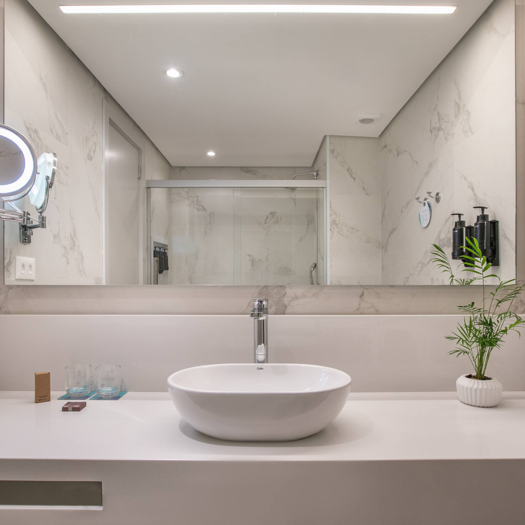 Modern bathroom vanity with vessel sink, large mirror, and marble walls.