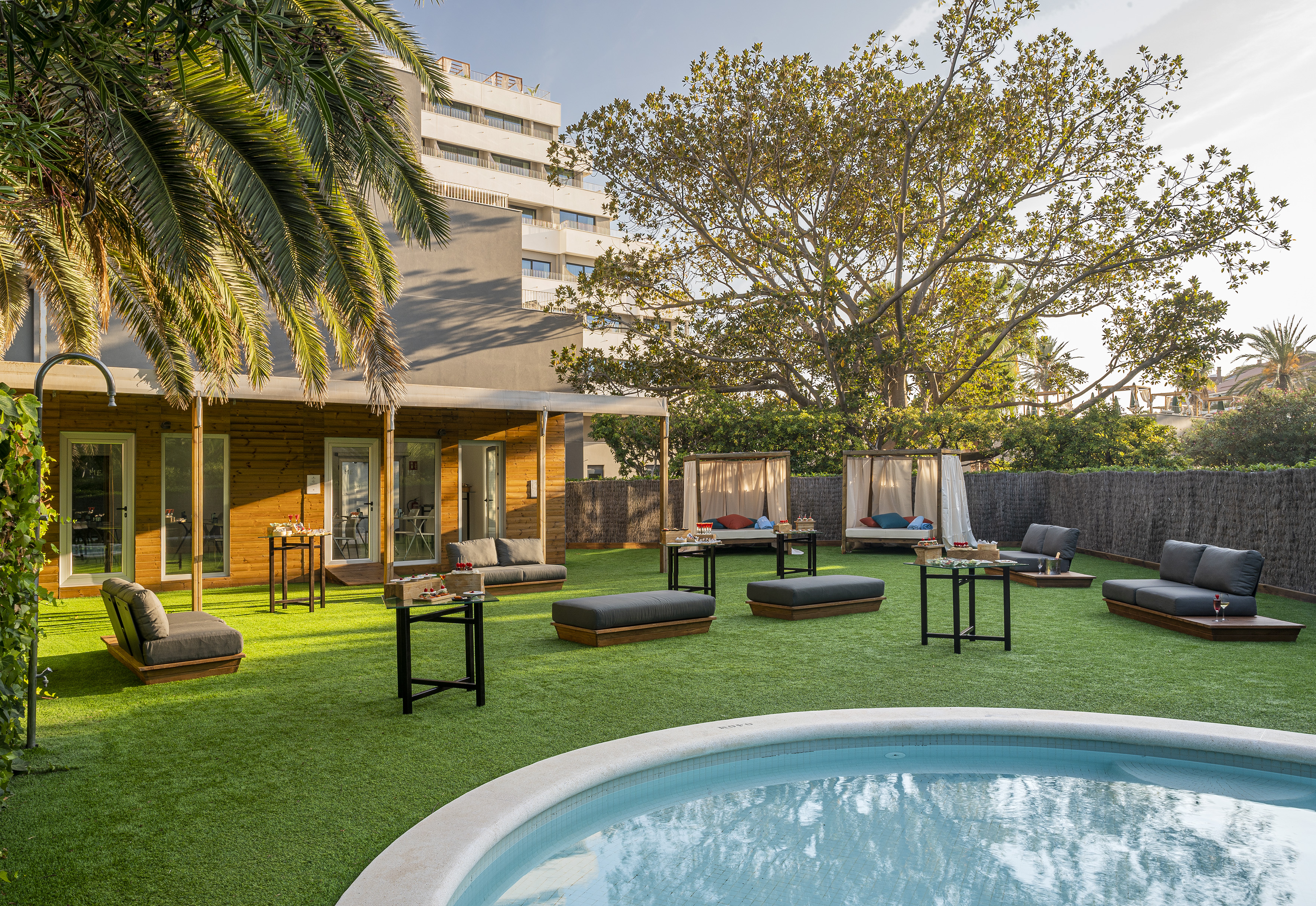 Hotel garden with pool, cabanas, and lounge seating on artificial grass.