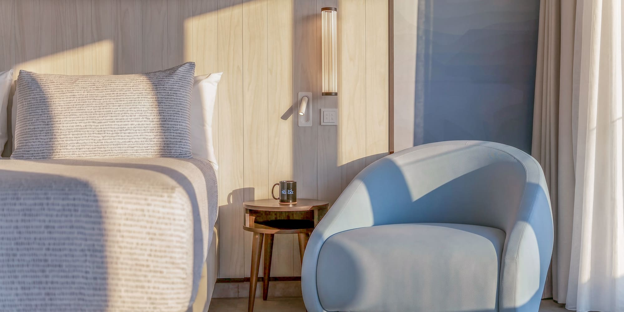 Modern bedroom with wood headboard, blue accent chair, and side table.