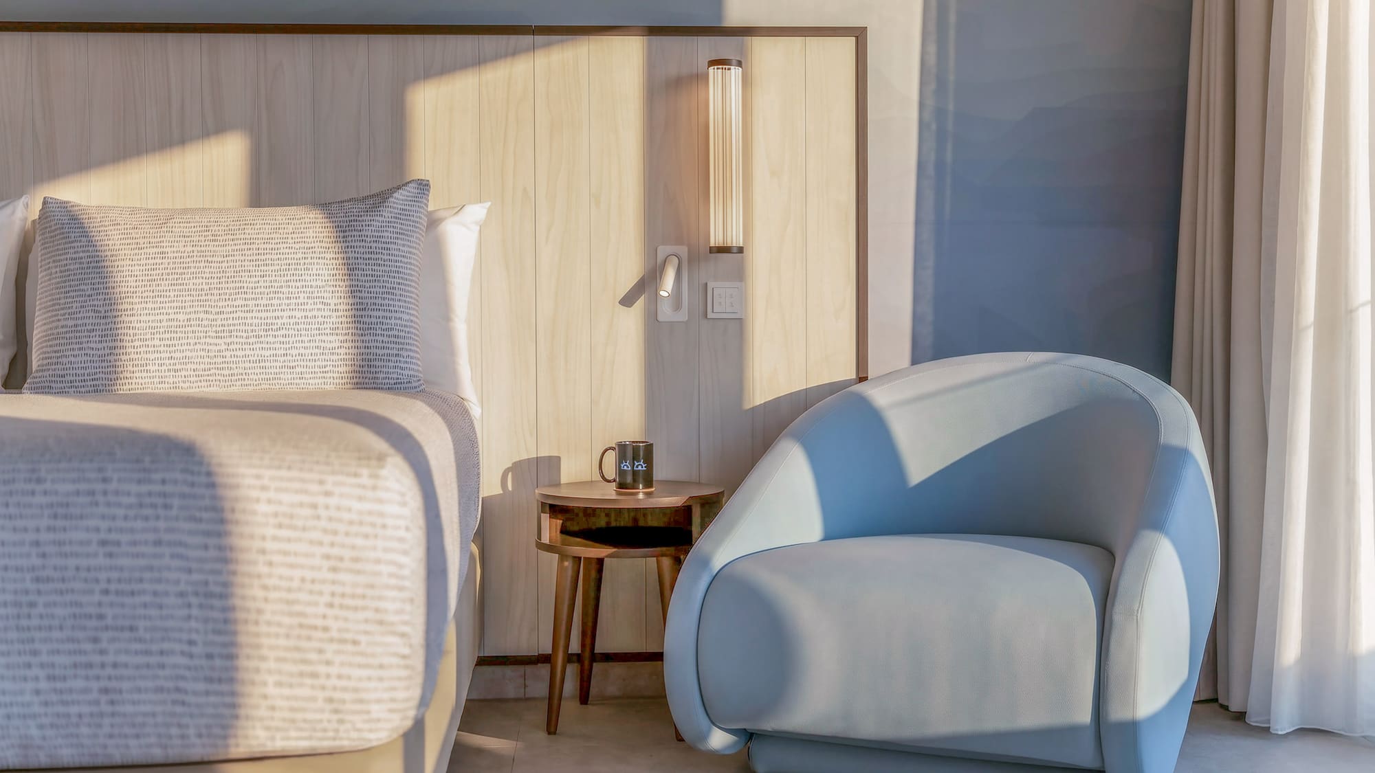 Modern bedroom with wood headboard, blue accent chair, and side table.