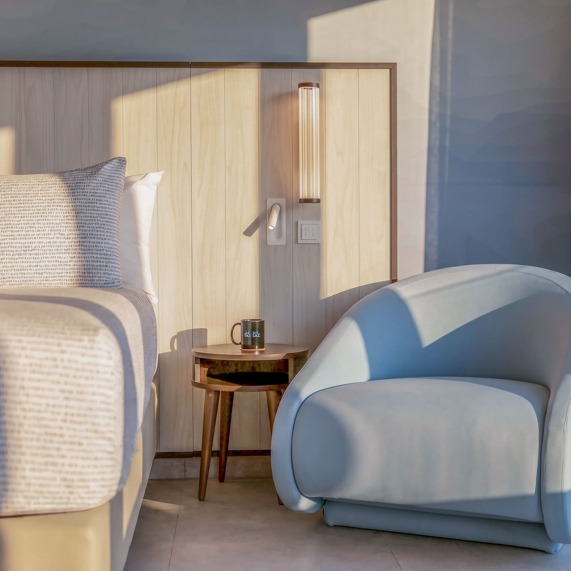 Modern bedroom with wood headboard, blue accent chair, and side table.