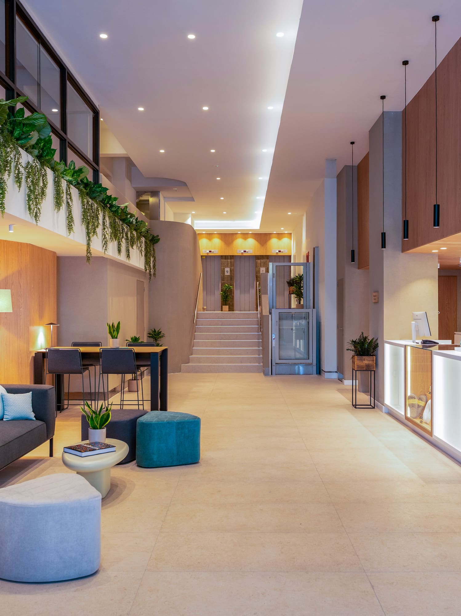 Vestíbulo moderno INNSIDE BY MELIA con pared vegetal, sofá y recepción.