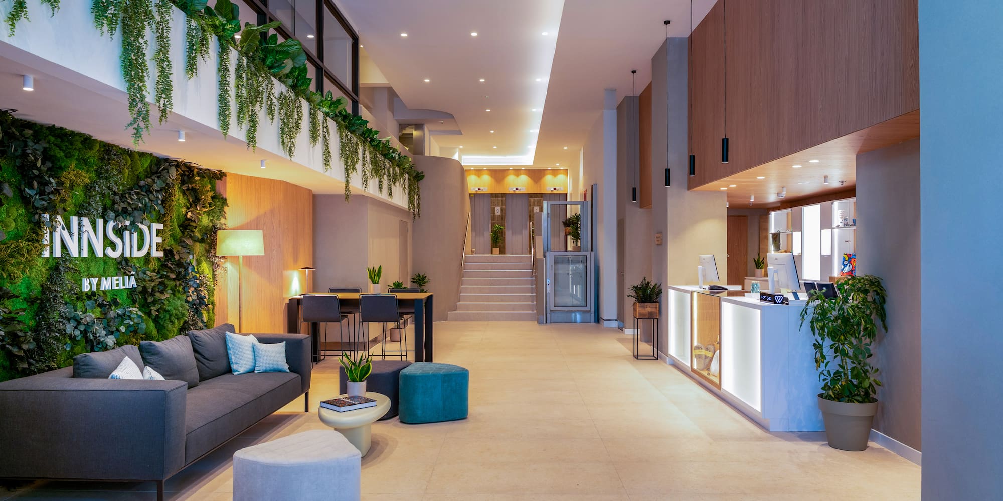 Lobby hotel INNSIDE BY MELIA: pared vegetal, sofá y mostrador recepción.