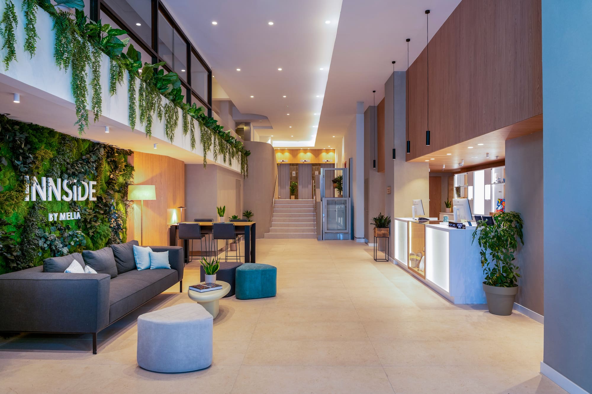 Lobby INNSIDE BY MELIA: diseño moderno con muro verde, sofá y mostrador.