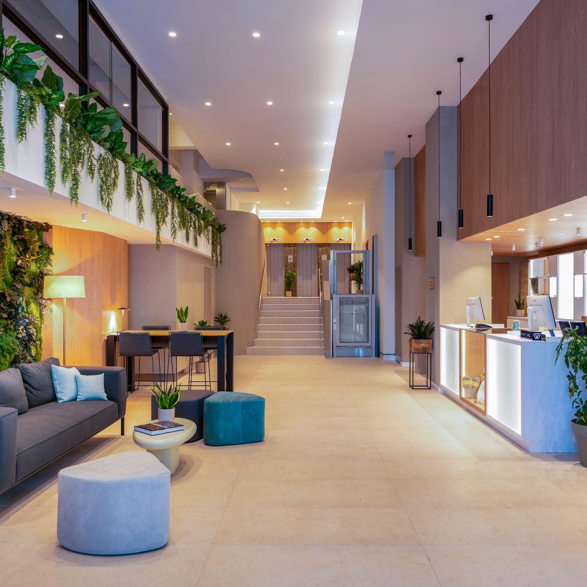 Vestíbulo moderno INNSIDE BY MELIA con pared vegetal, sofá y recepción.