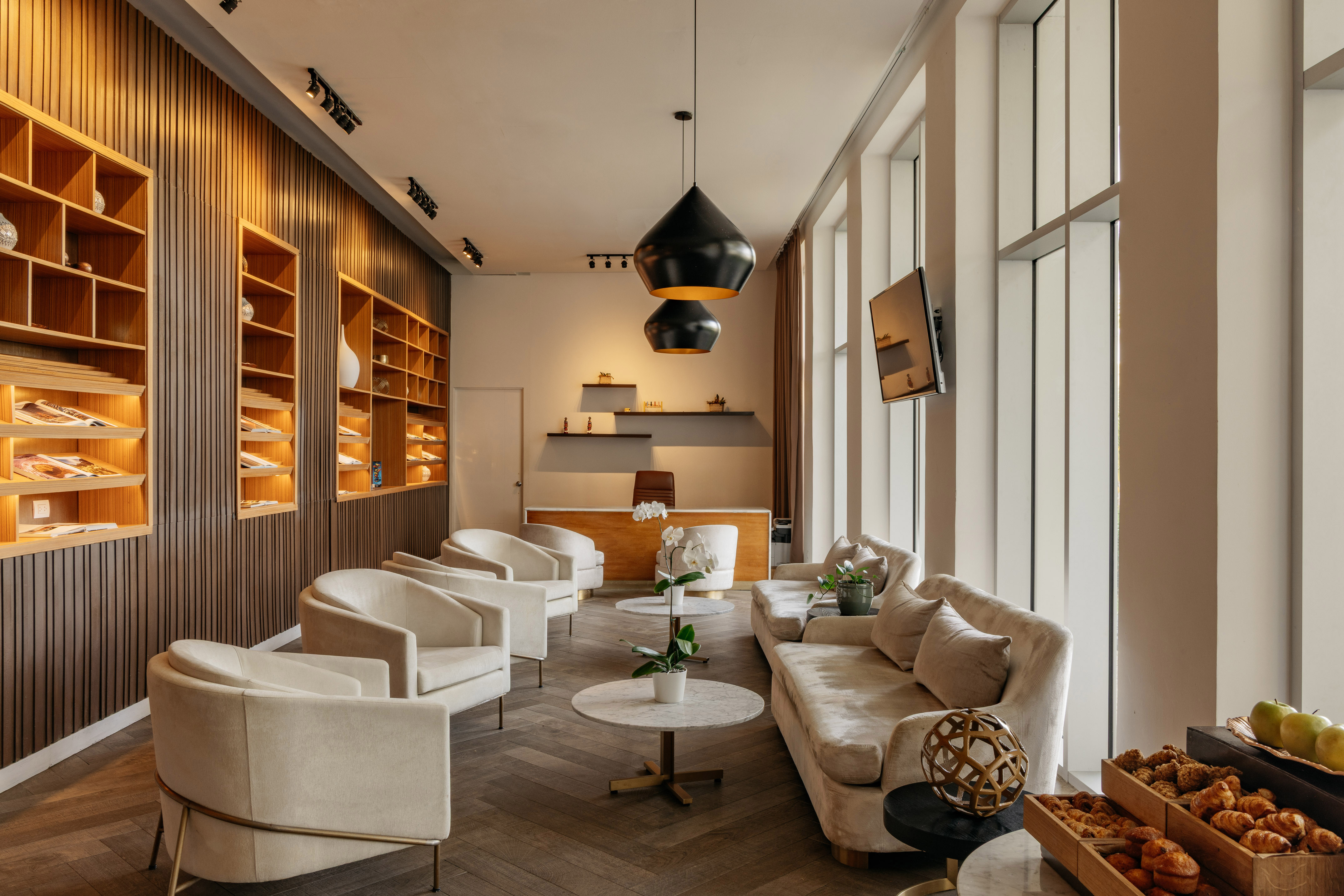Modern hotel lobby with cream seating, wooden slat walls, and a reception desk.