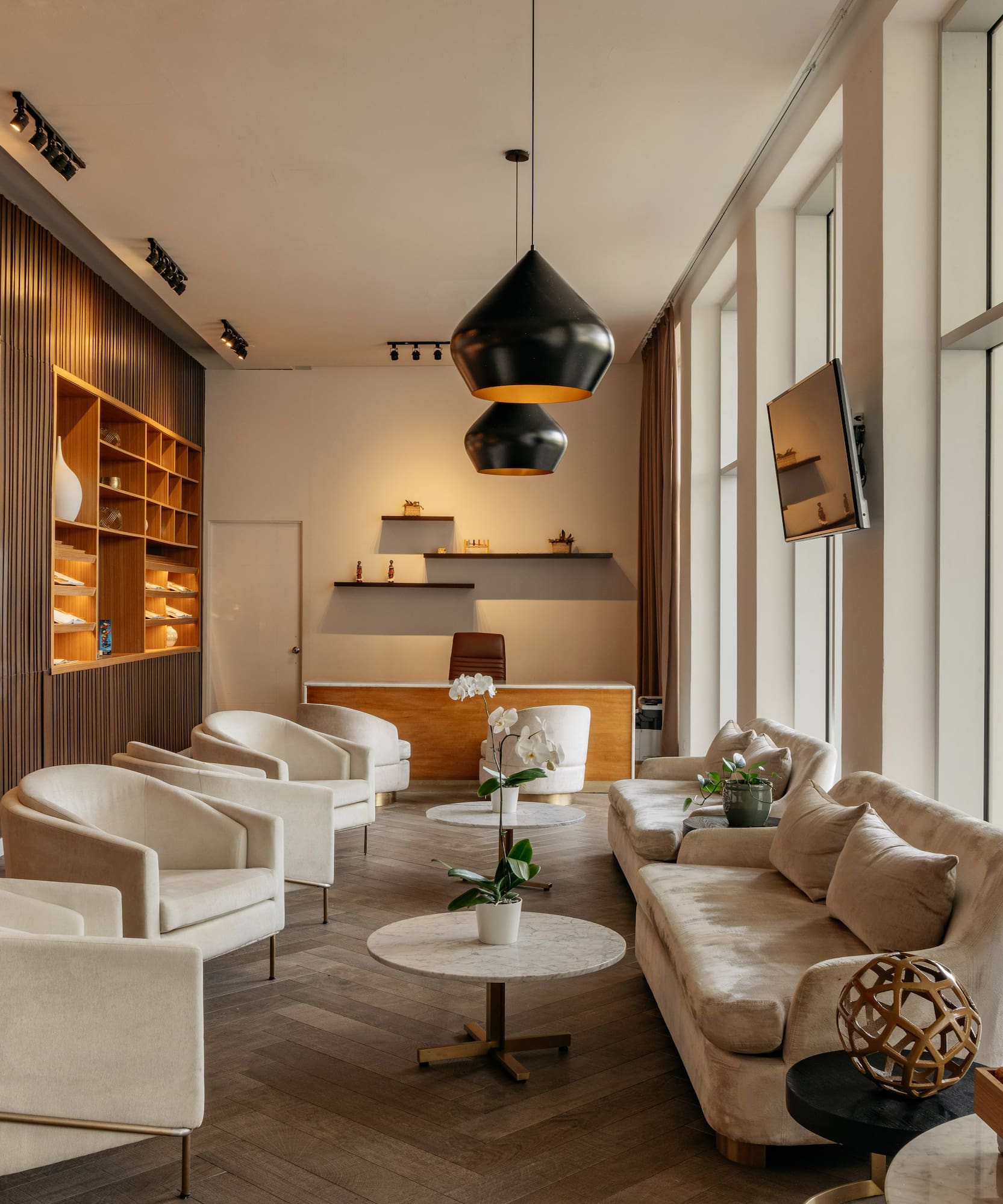 Modern hotel lobby with cream seating, wooden slat walls, and a reception desk.