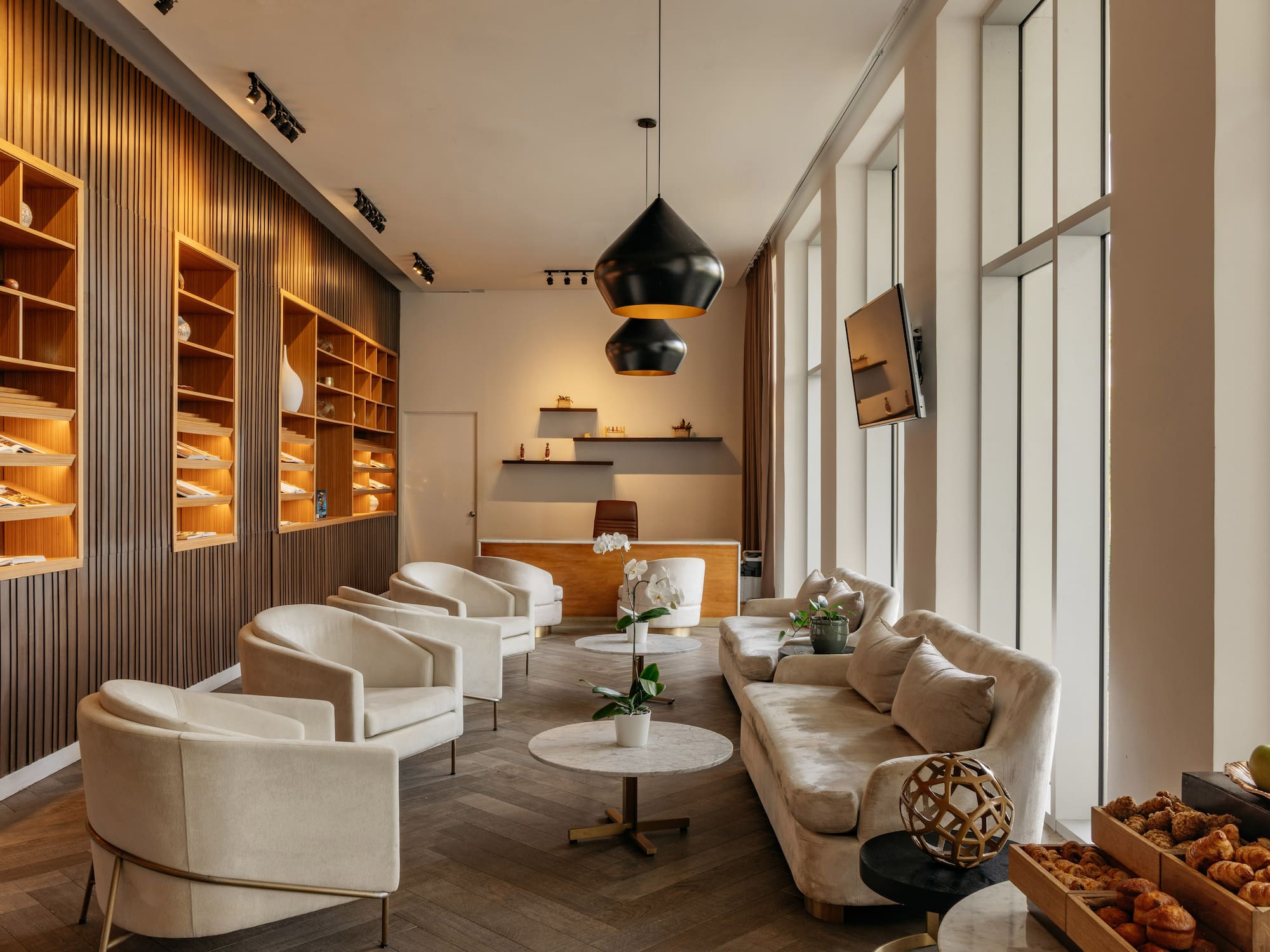 Modern hotel lobby with cream seating, wooden slat walls, and a reception desk.