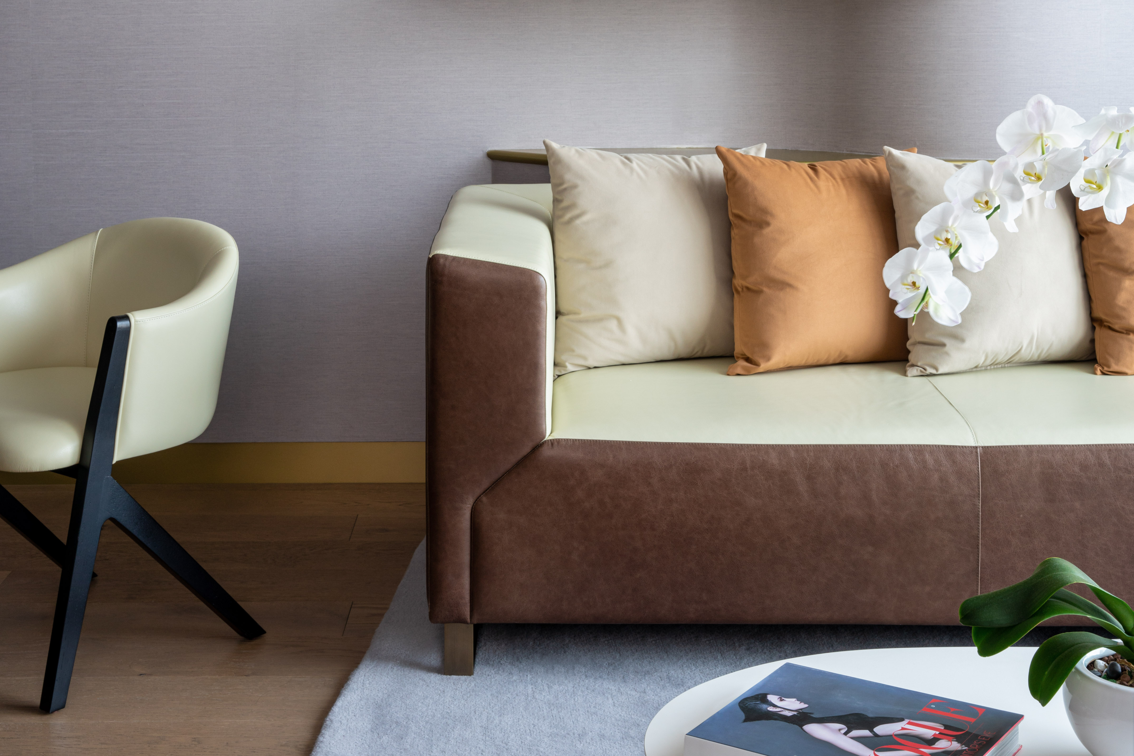 Brown & cream leather sofa, cushions, white orchids, modern armchair.