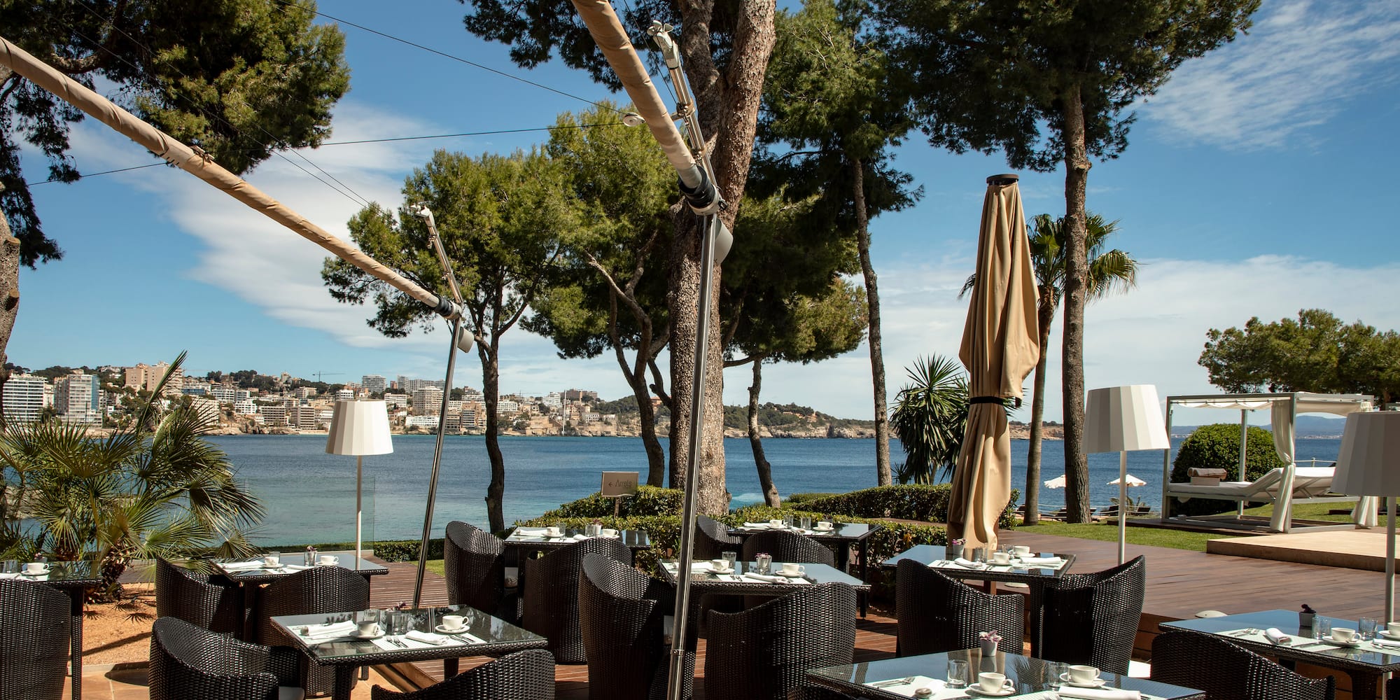 a restaurant with tables and chairs on a deck with trees and water in the background