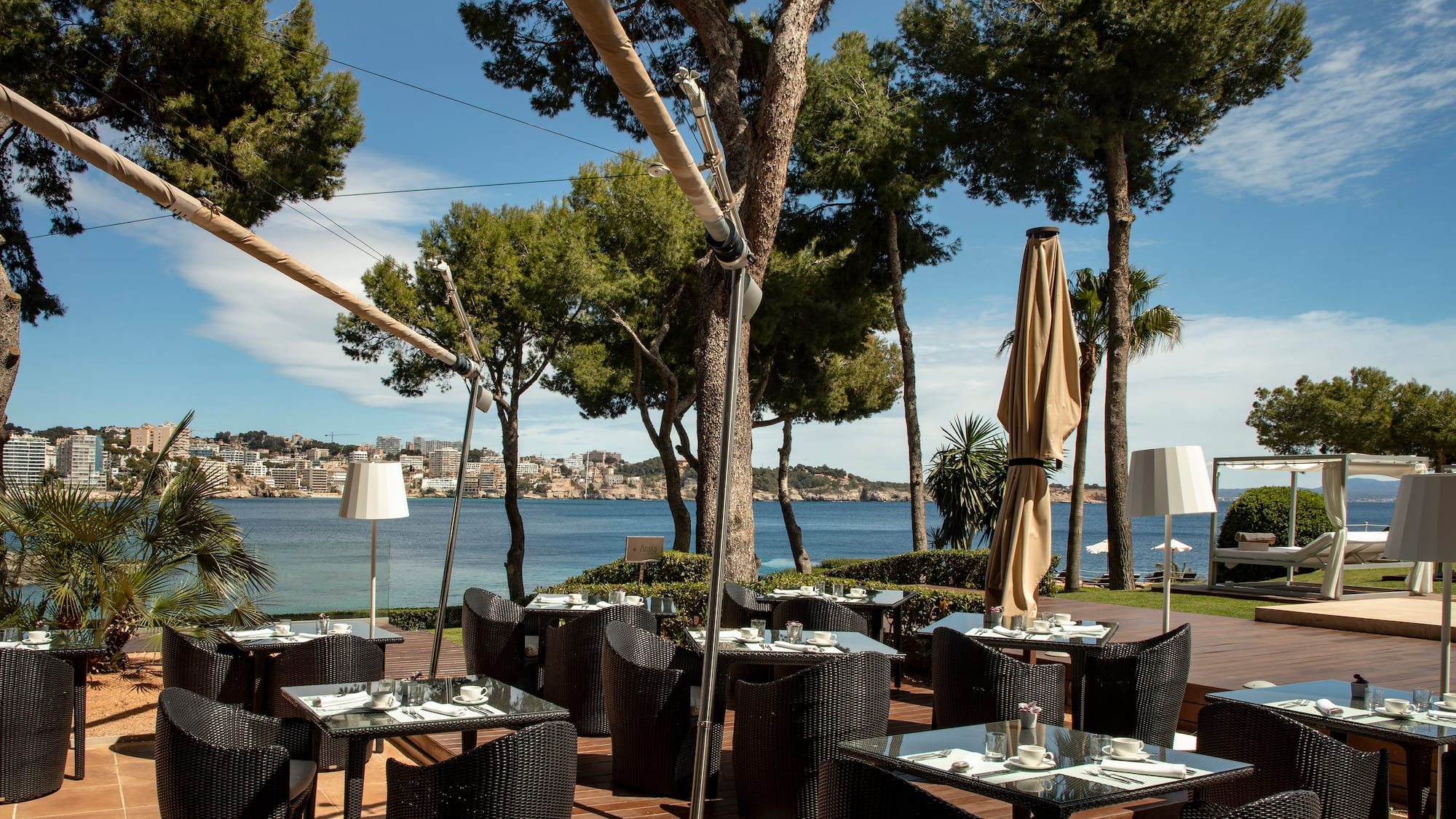 a restaurant with tables and chairs on a deck with trees and water in the background