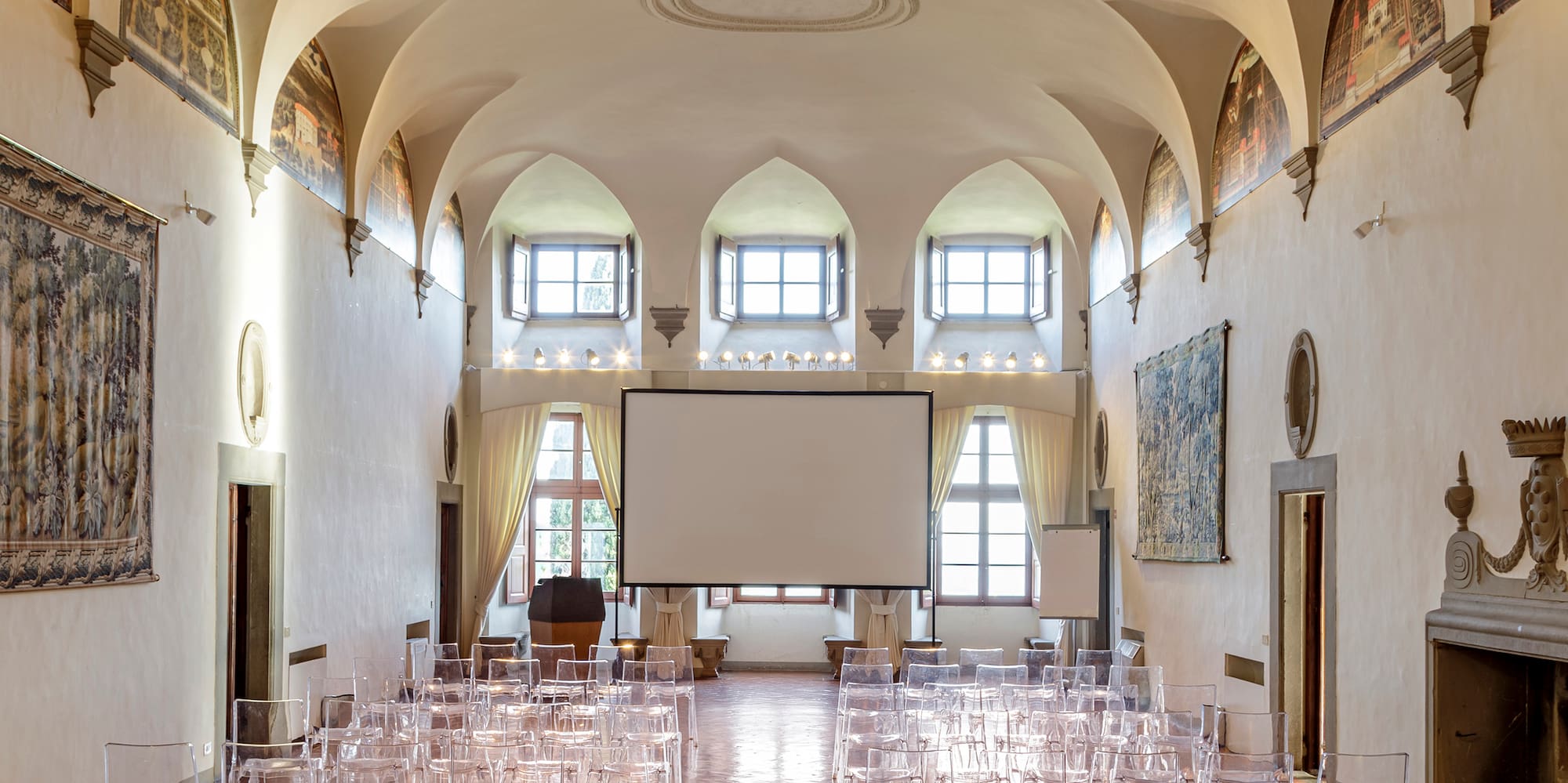 a room with many clear chairs and a projector screen
