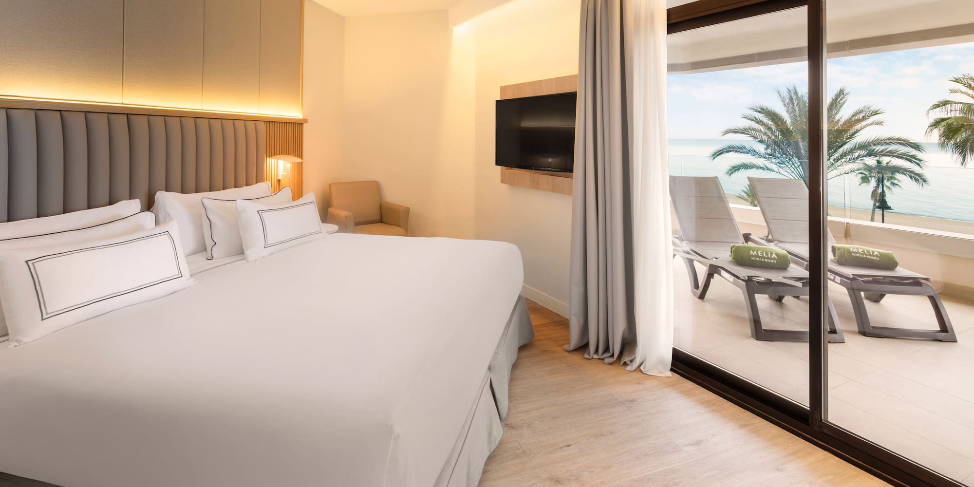 a bed with a glass door leading to a beach