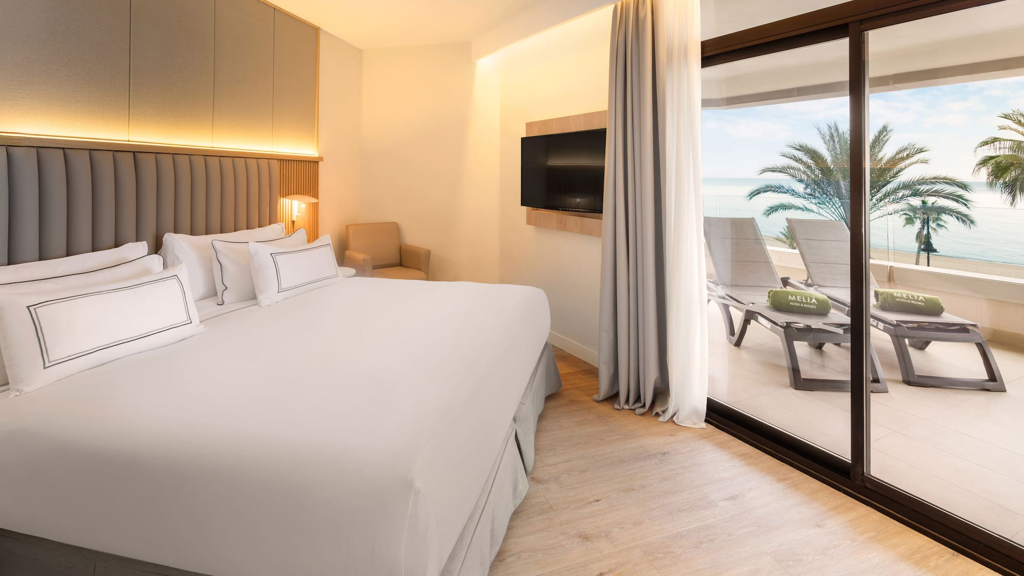 a bed with a glass door leading to a beach