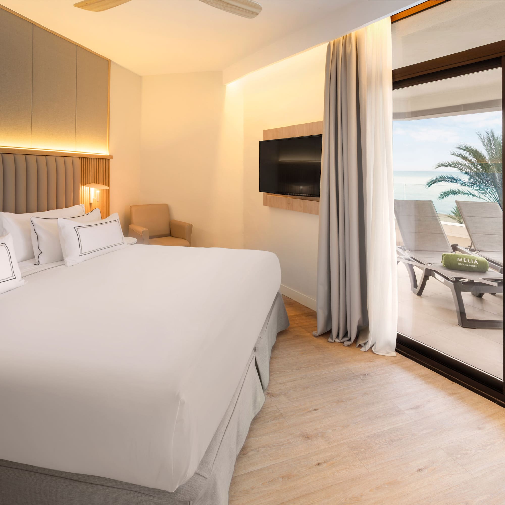 a bed with a glass door leading to a beach