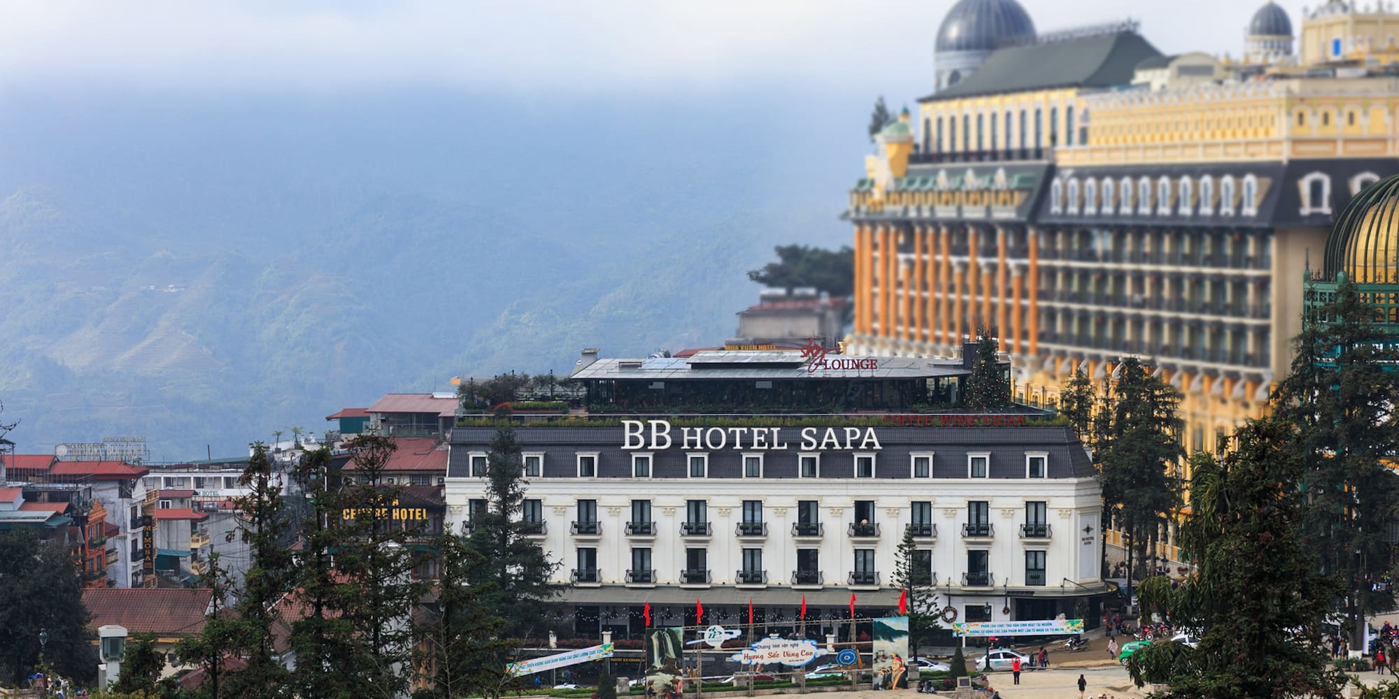 a building with a dome roof and a large building with trees and mountains in the background