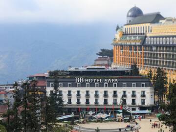a building with a dome roof and a large building with trees and mountains in the background