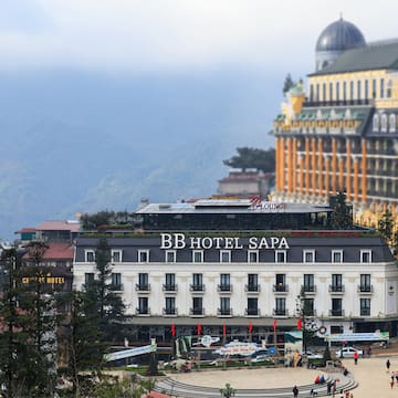 a building with a dome roof and a large building with trees and mountains in the background