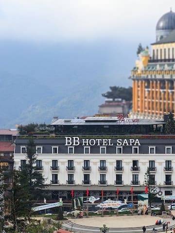a building with a dome roof and a large building with trees and mountains in the background