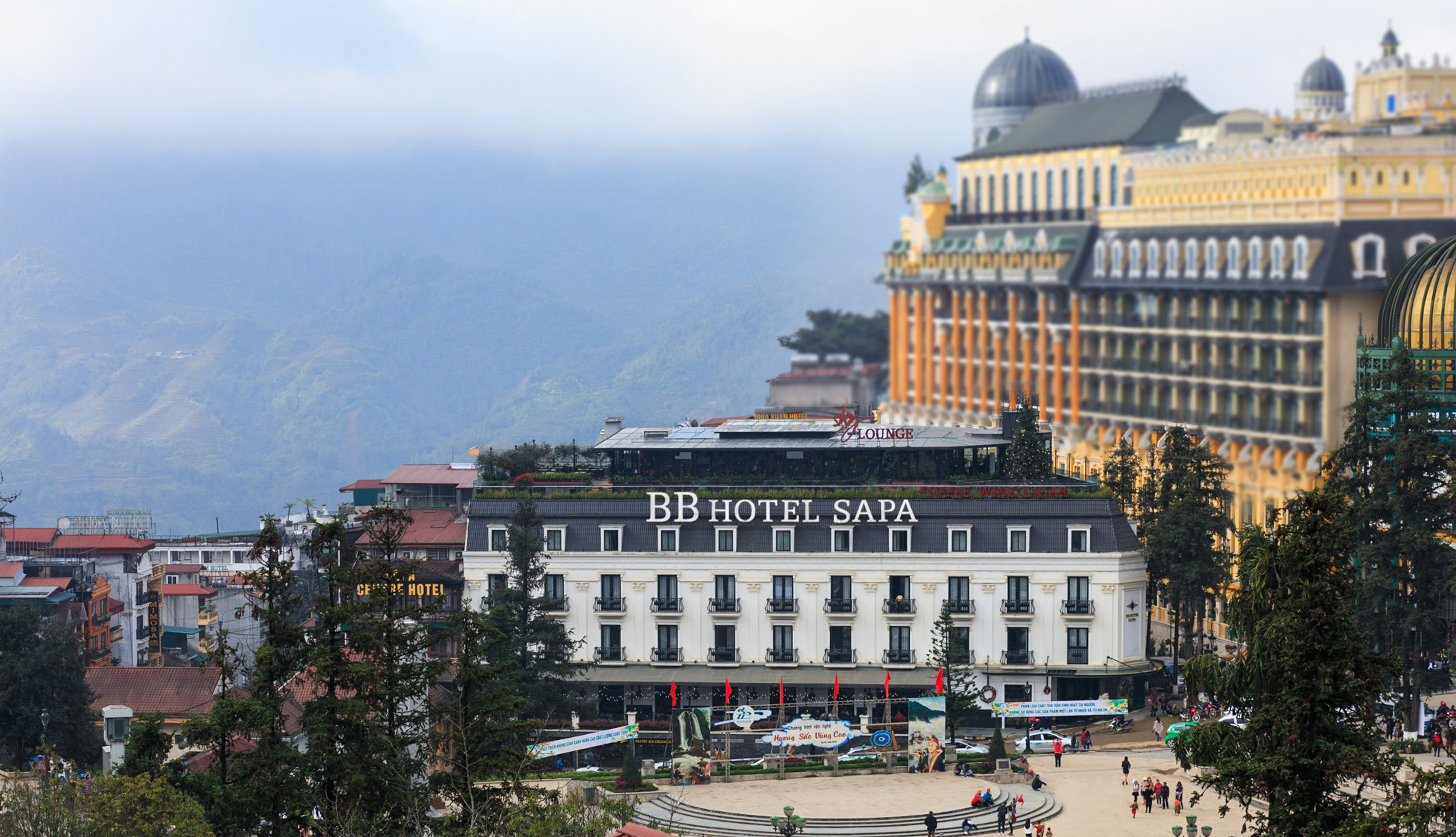 a building with a dome roof and a large building with trees and mountains in the background