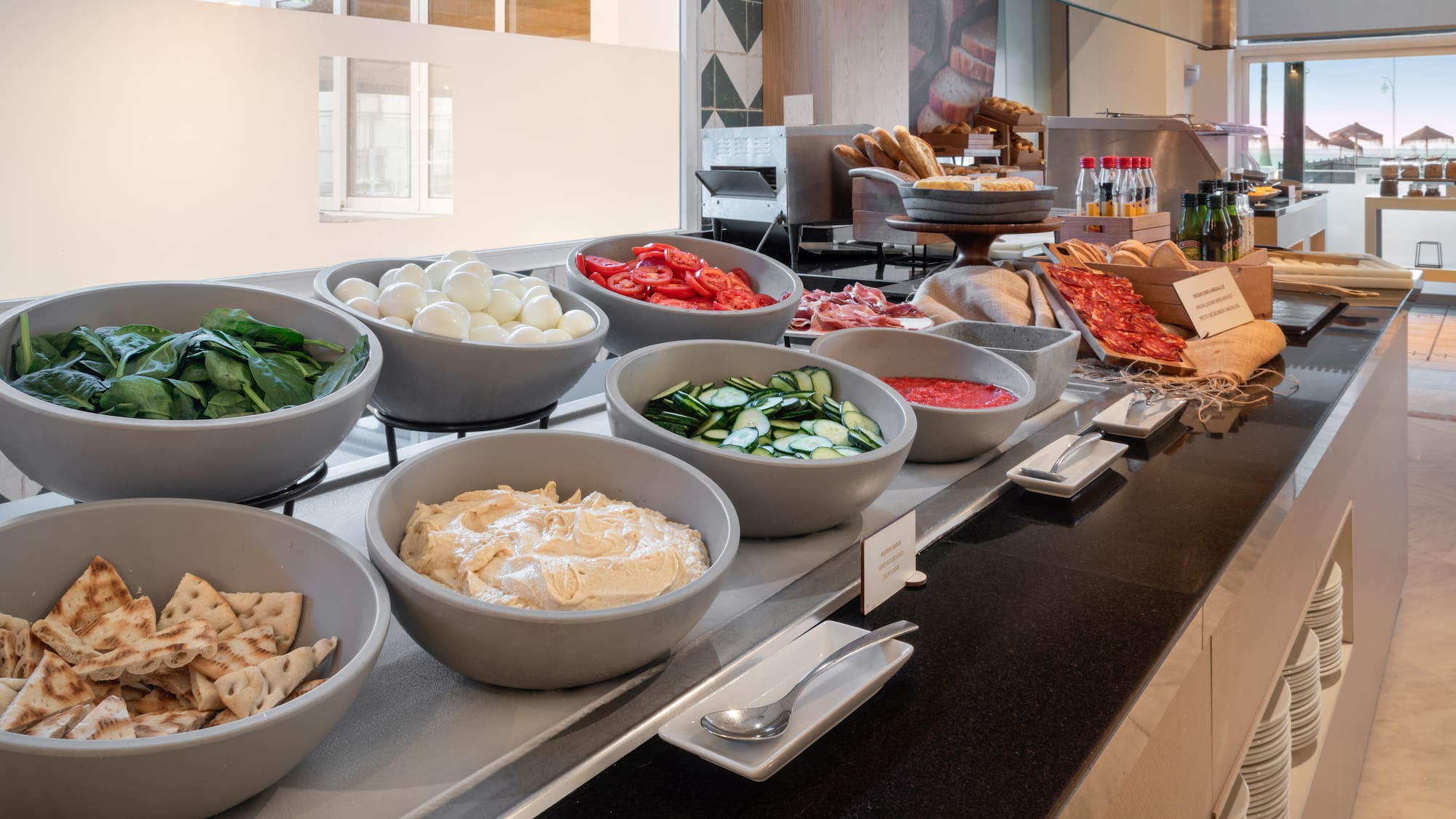 Hotel buffet with fresh spinach, boiled eggs, tomatoes, hummus, pita, and meats.