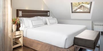a bed with white sheets and a brown bedding