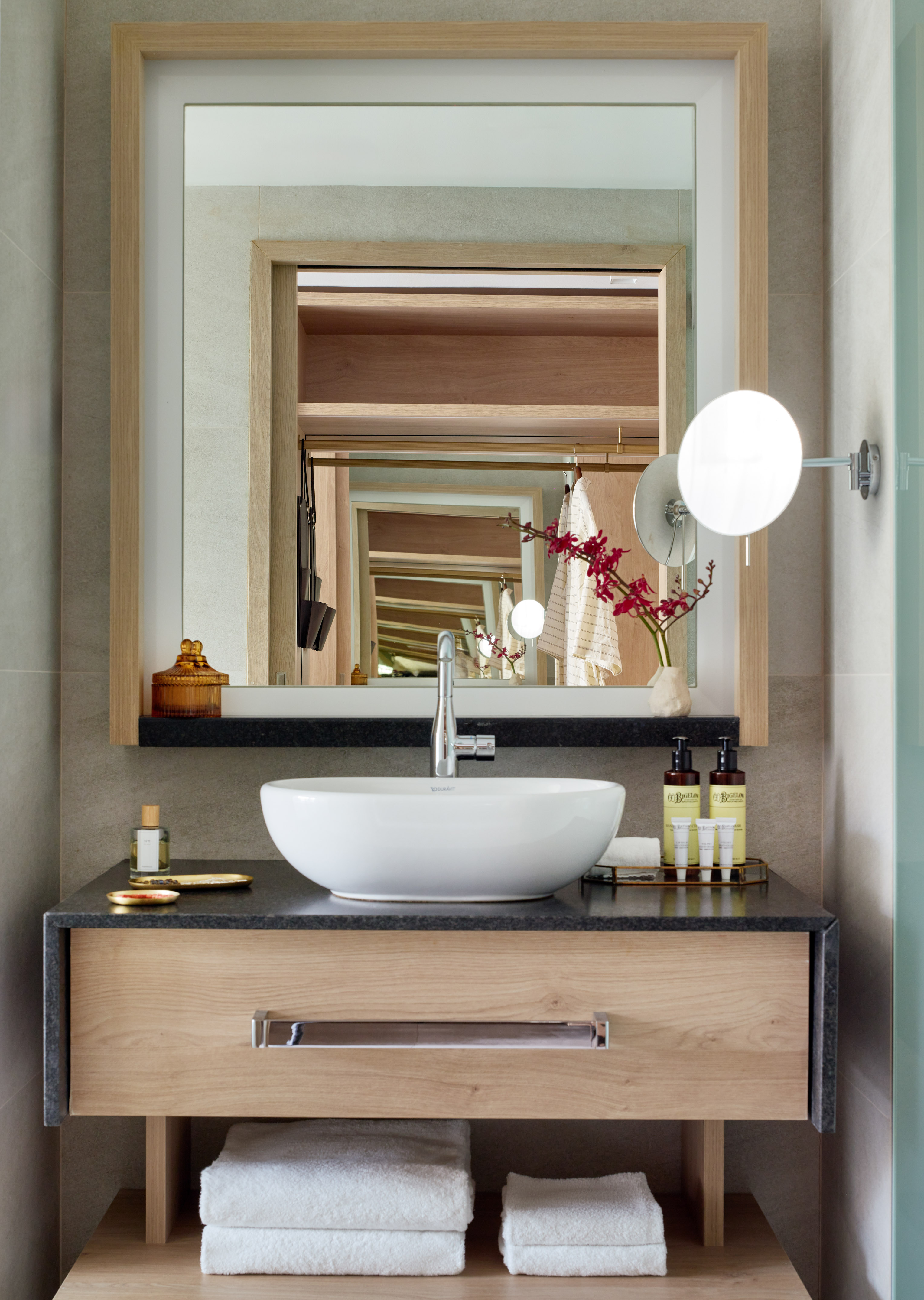 Modern wood bathroom vanity, vessel sink, stone counter, framed mirror, hotel.
