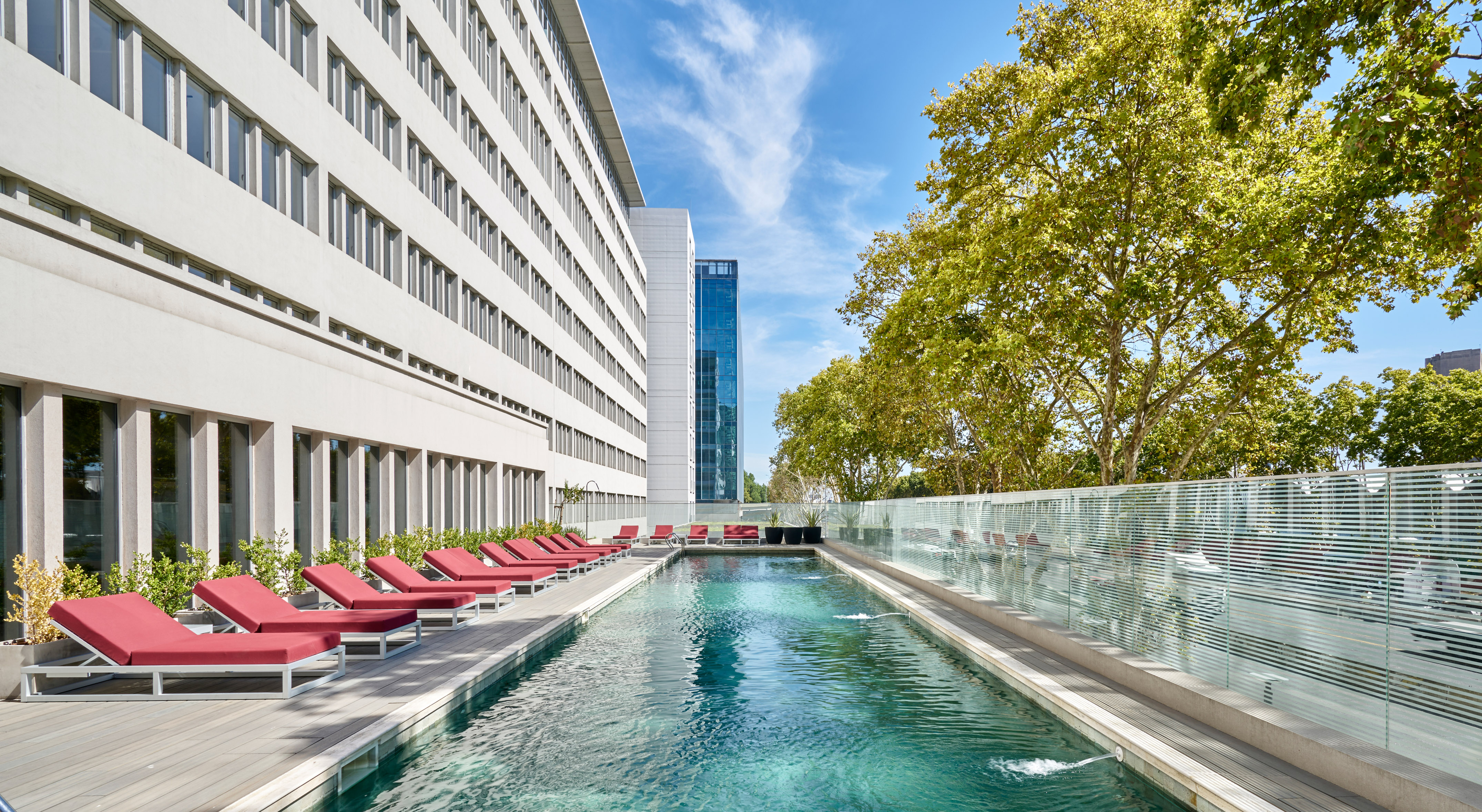 a pool with chairs and a building in the background