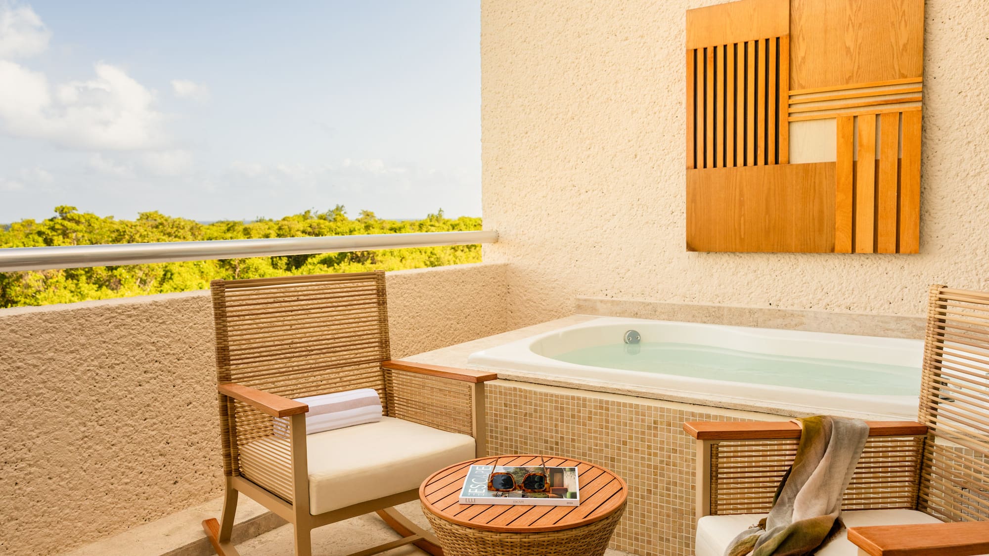 Hotel balcony with private jacuzzi, outdoor seating, and lush tropical view.