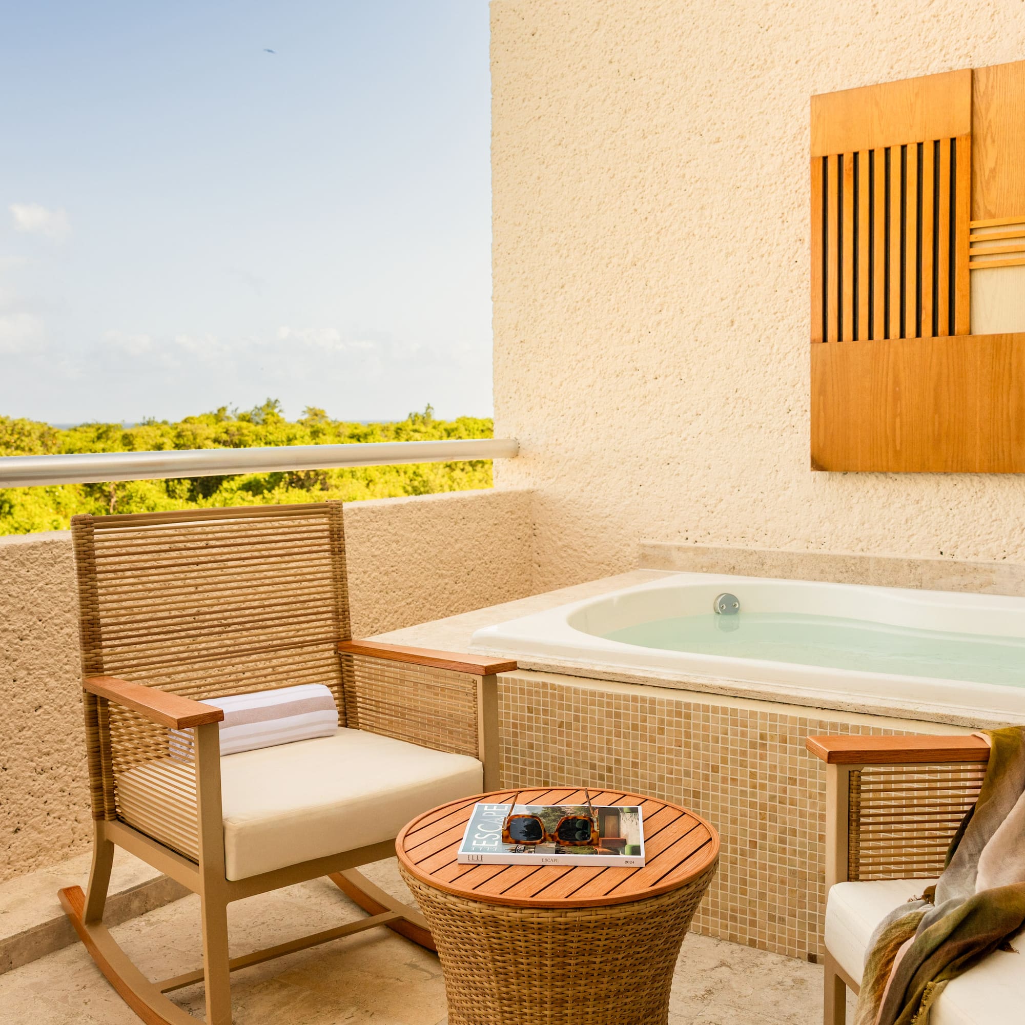 Hotel balcony with private hot tub, lounge chairs, and lush tropical view.