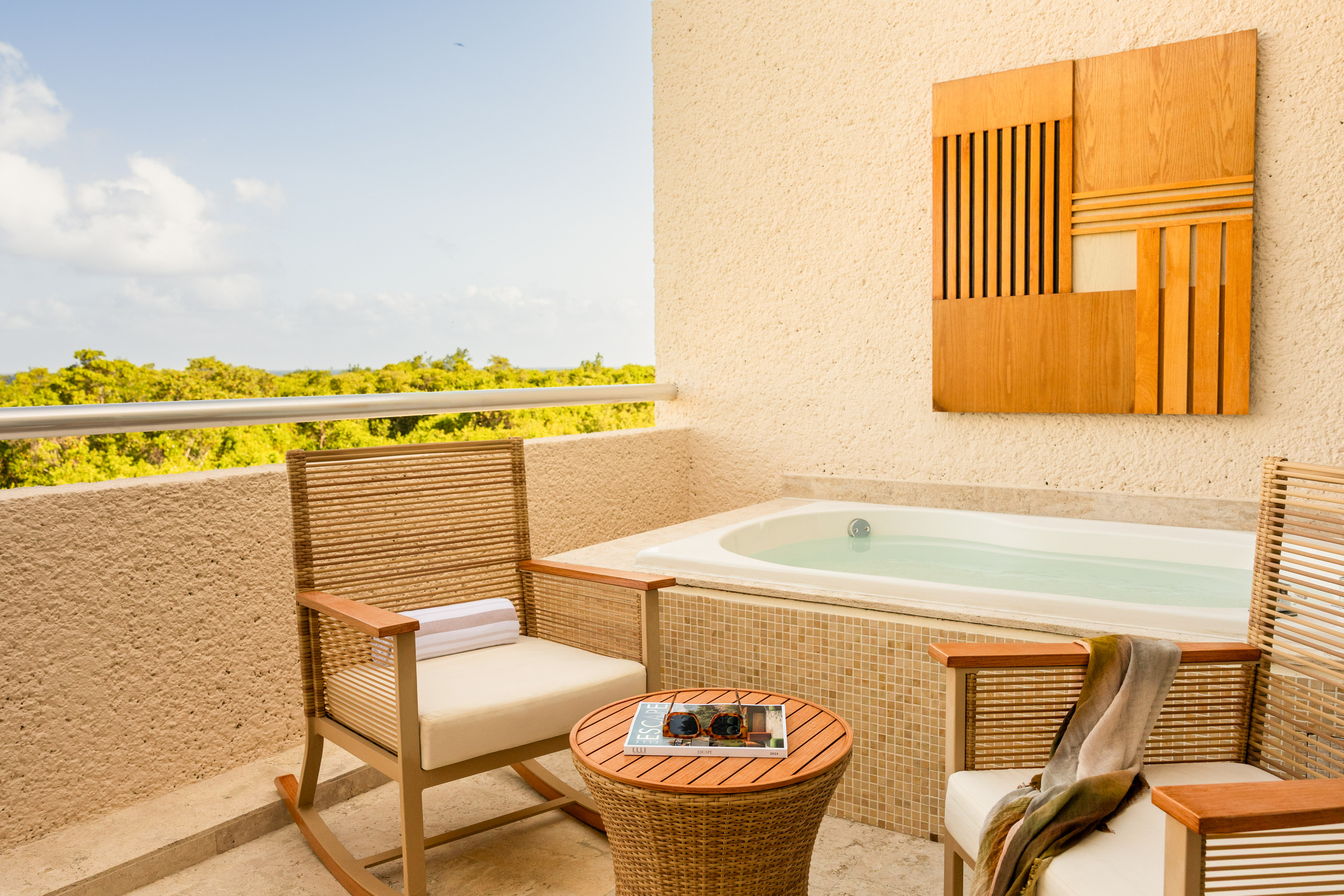 Hotel balcony with private hot tub, lounge chairs, and lush tropical view.