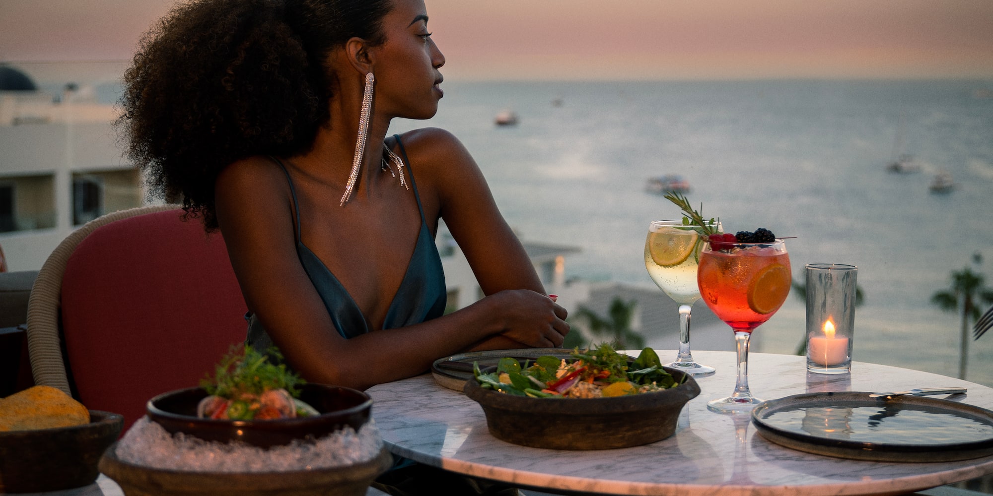 a woman sitting at a table with a bowl of food and drinks