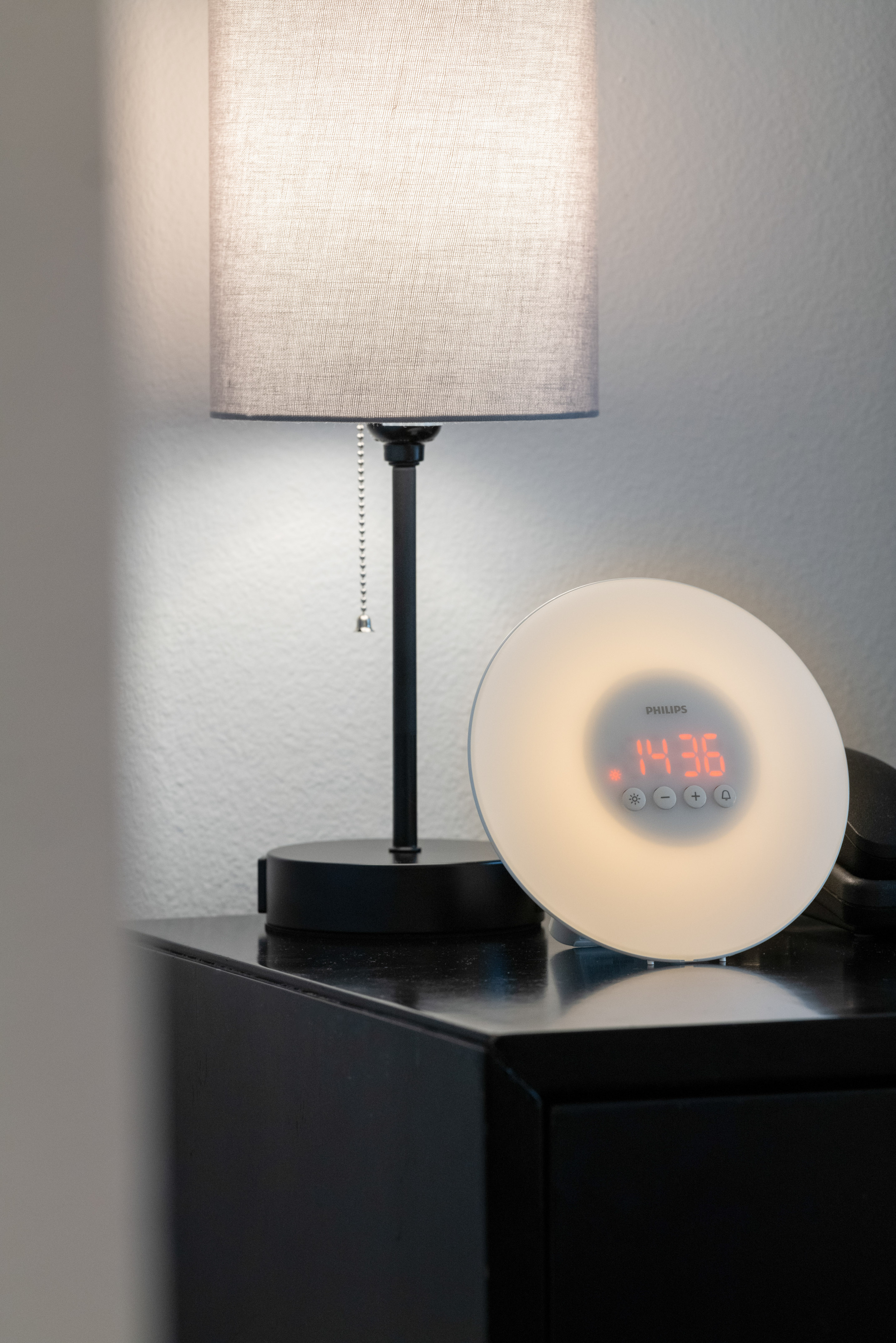 Philips Wake-up Light alarm clock and bedside lamp on a dark nightstand.