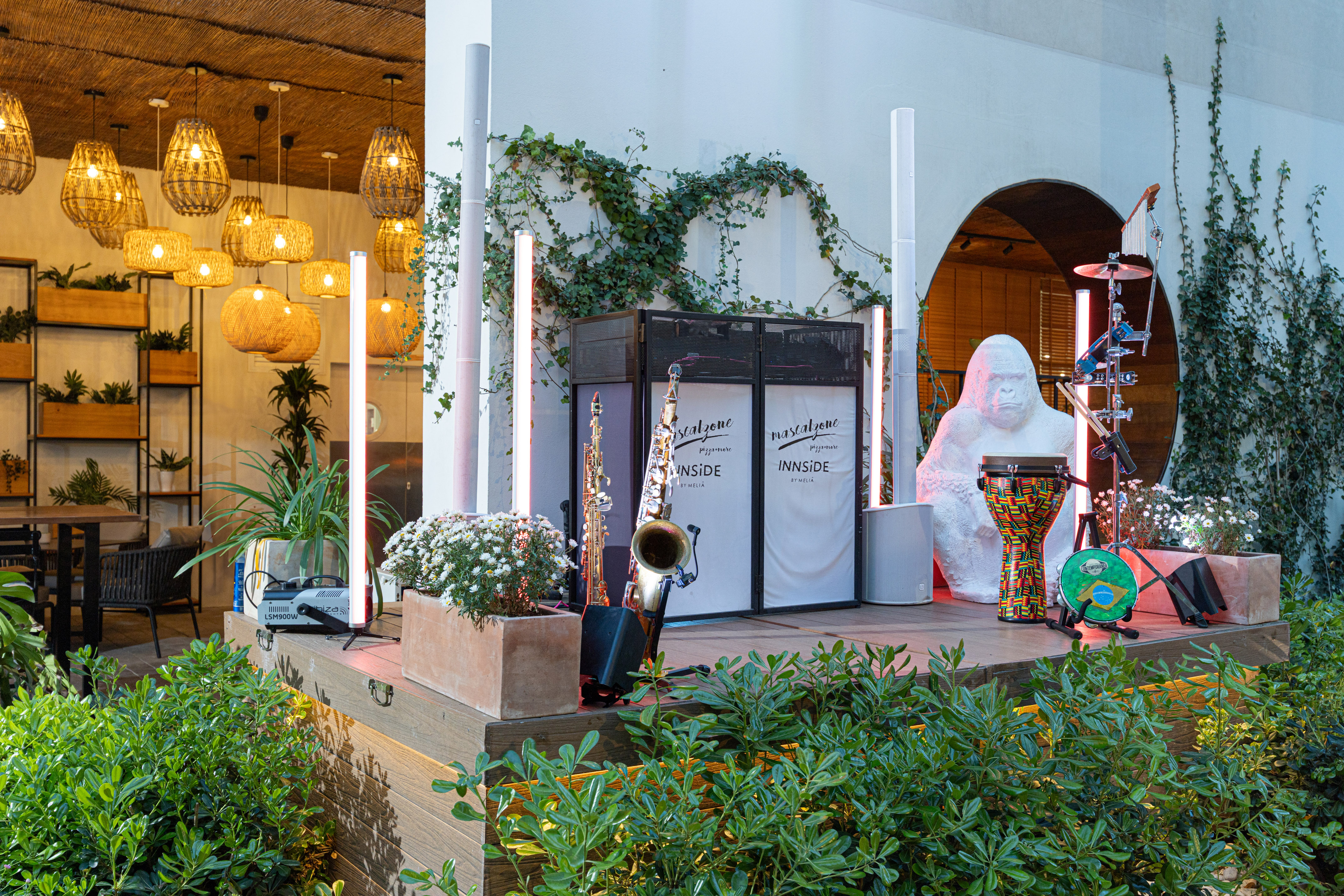 Tropical live music stage with saxophone, djembe, white gorilla statue at hotel.