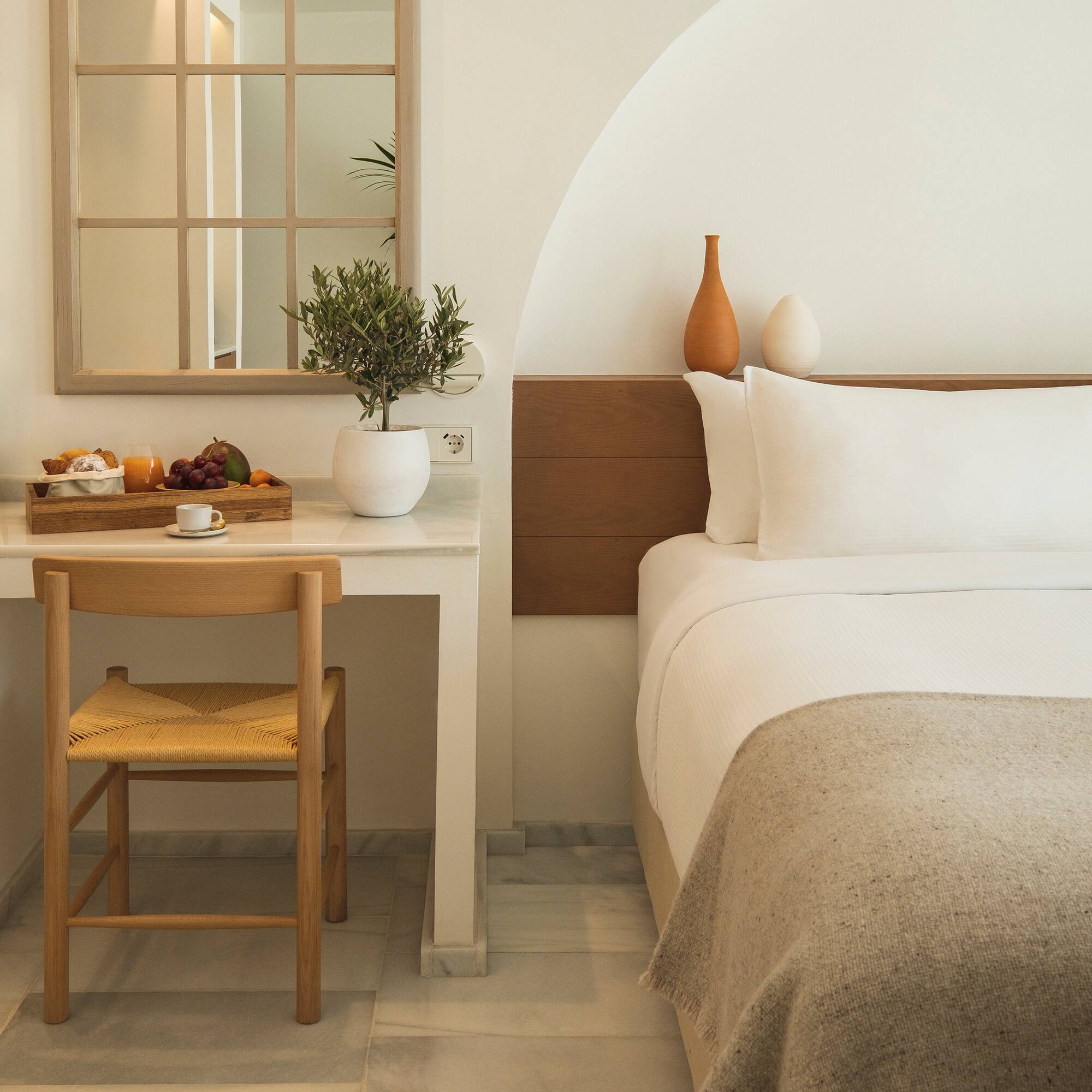 a bed with a chair and a table with a plant on it