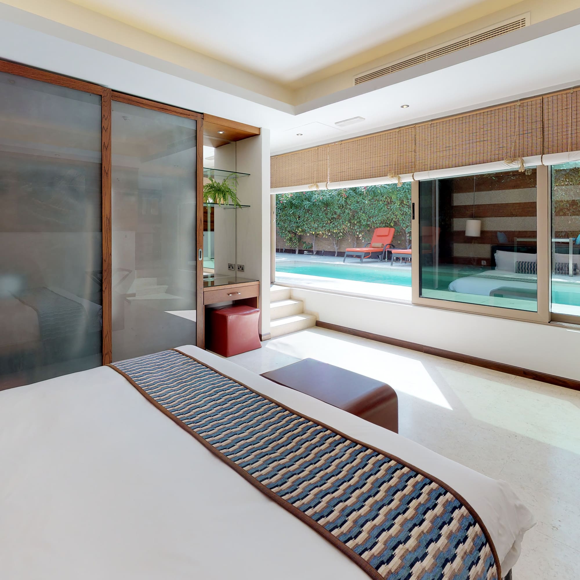 a bedroom with a bed and a pool in the background