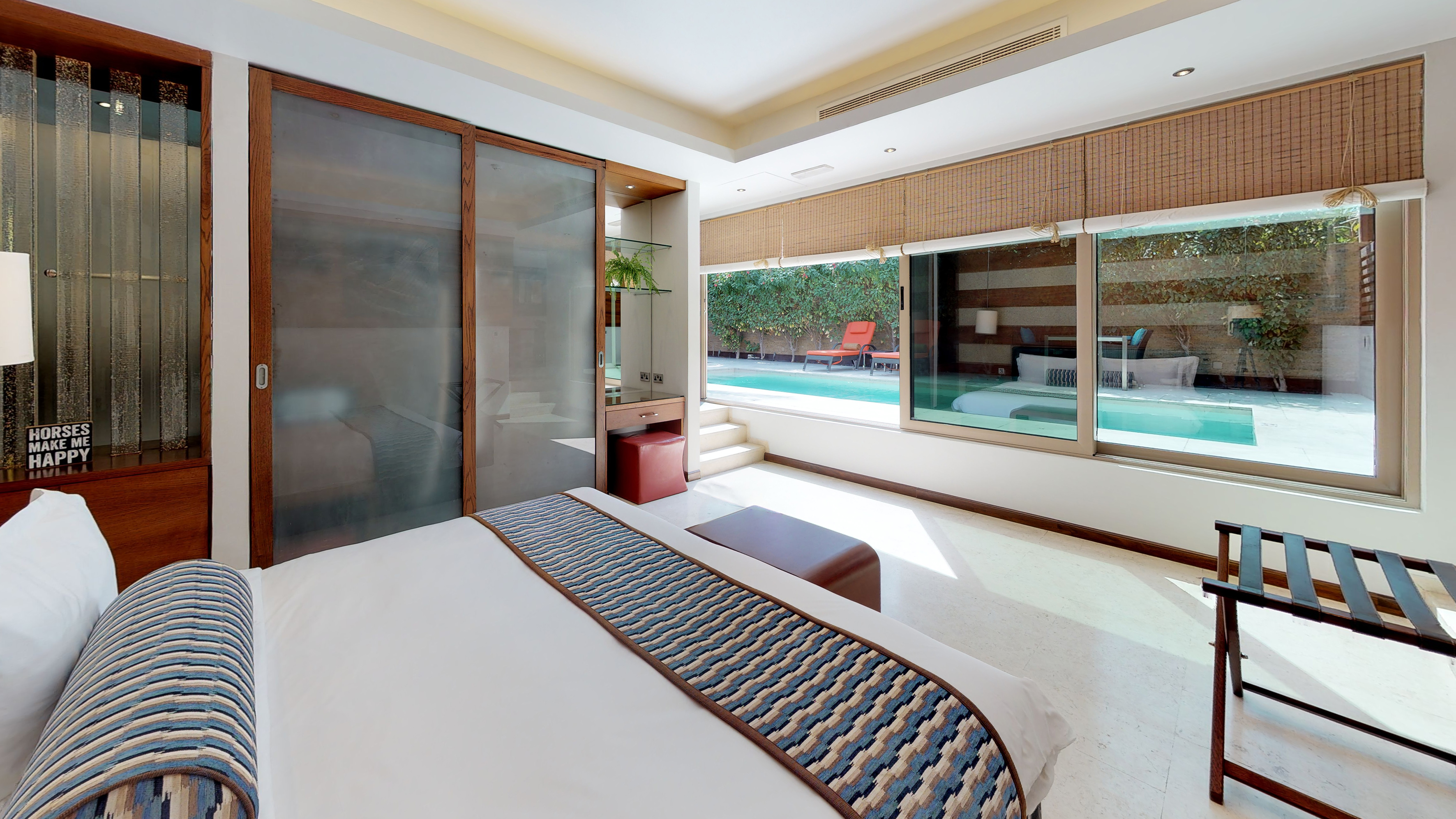 Luxury hotel bedroom with large windows overlooking a private pool.