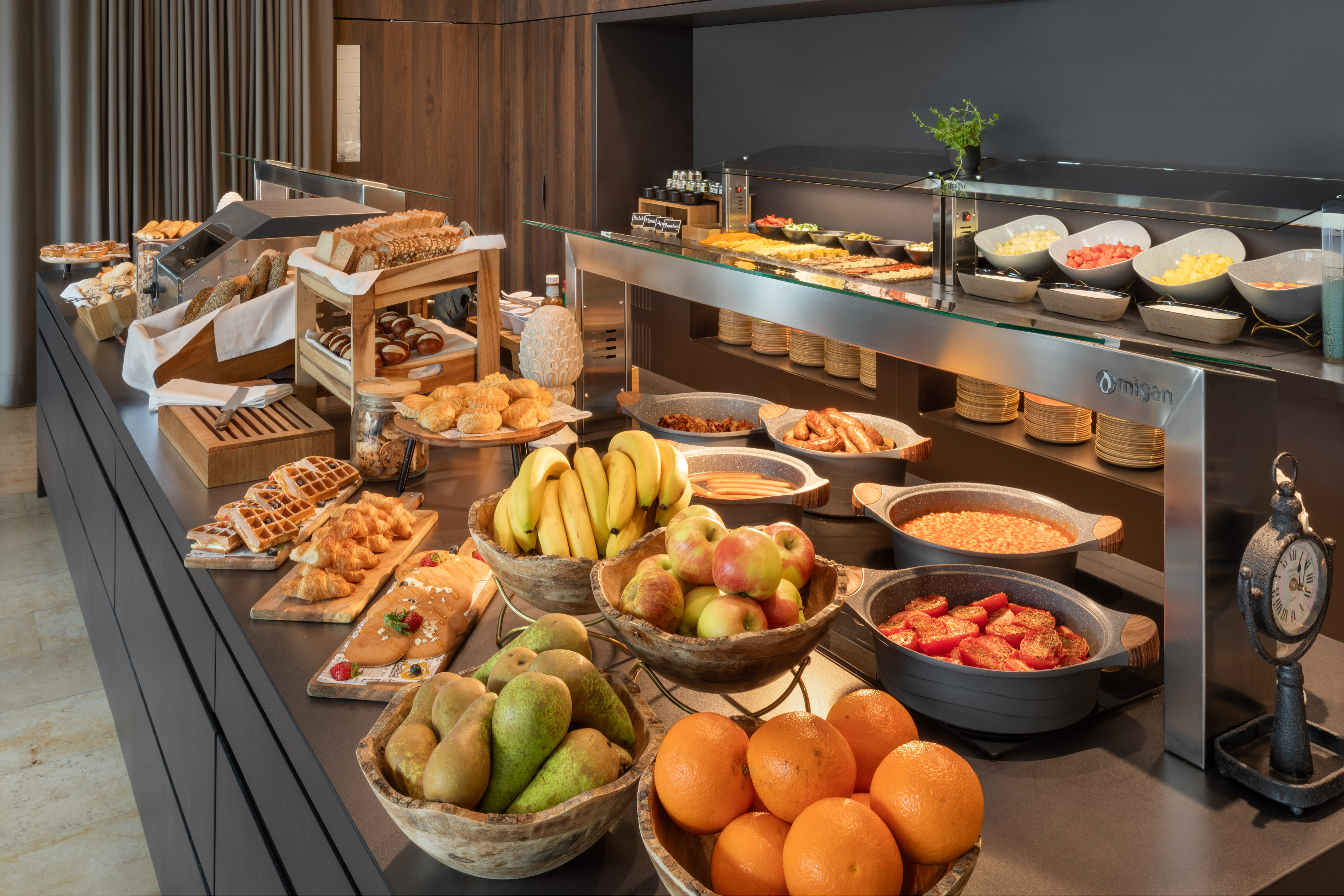 Abundant hotel breakfast buffet with fresh fruits, pastries, hot dishes, and breads.