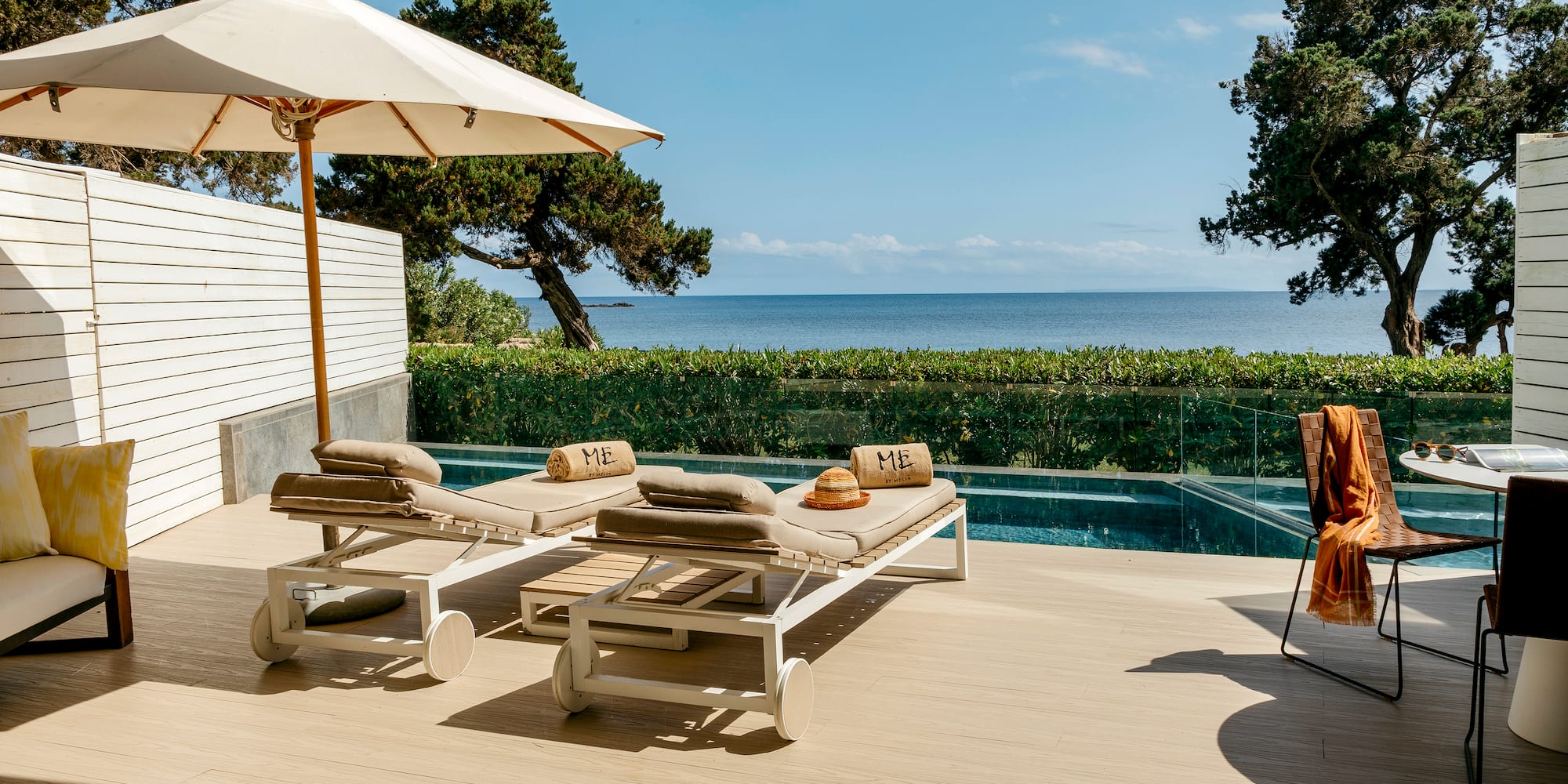 a deck with chairs and umbrellas on a deck overlooking a body of water