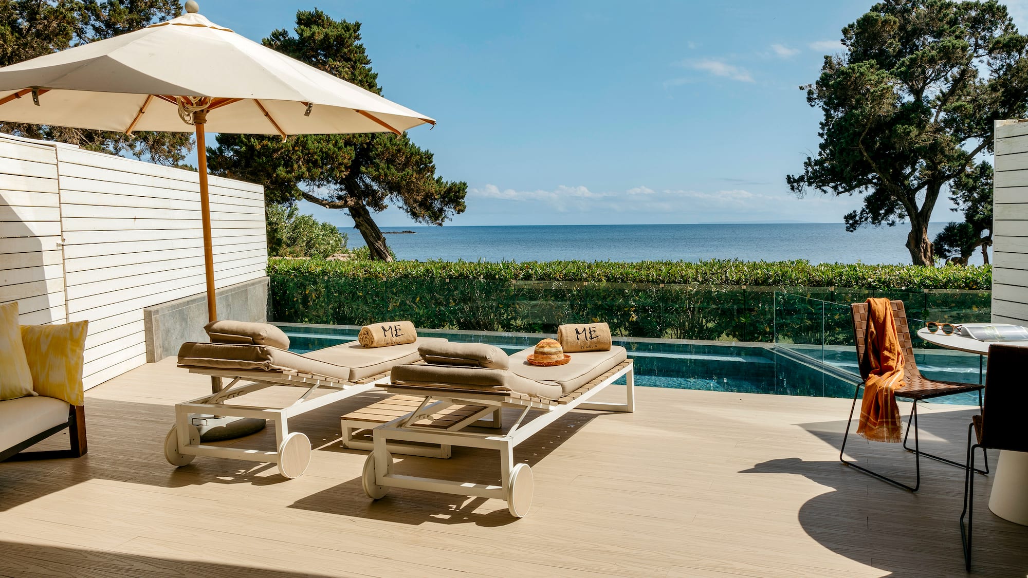 a deck with chairs and umbrellas on a deck overlooking a body of water