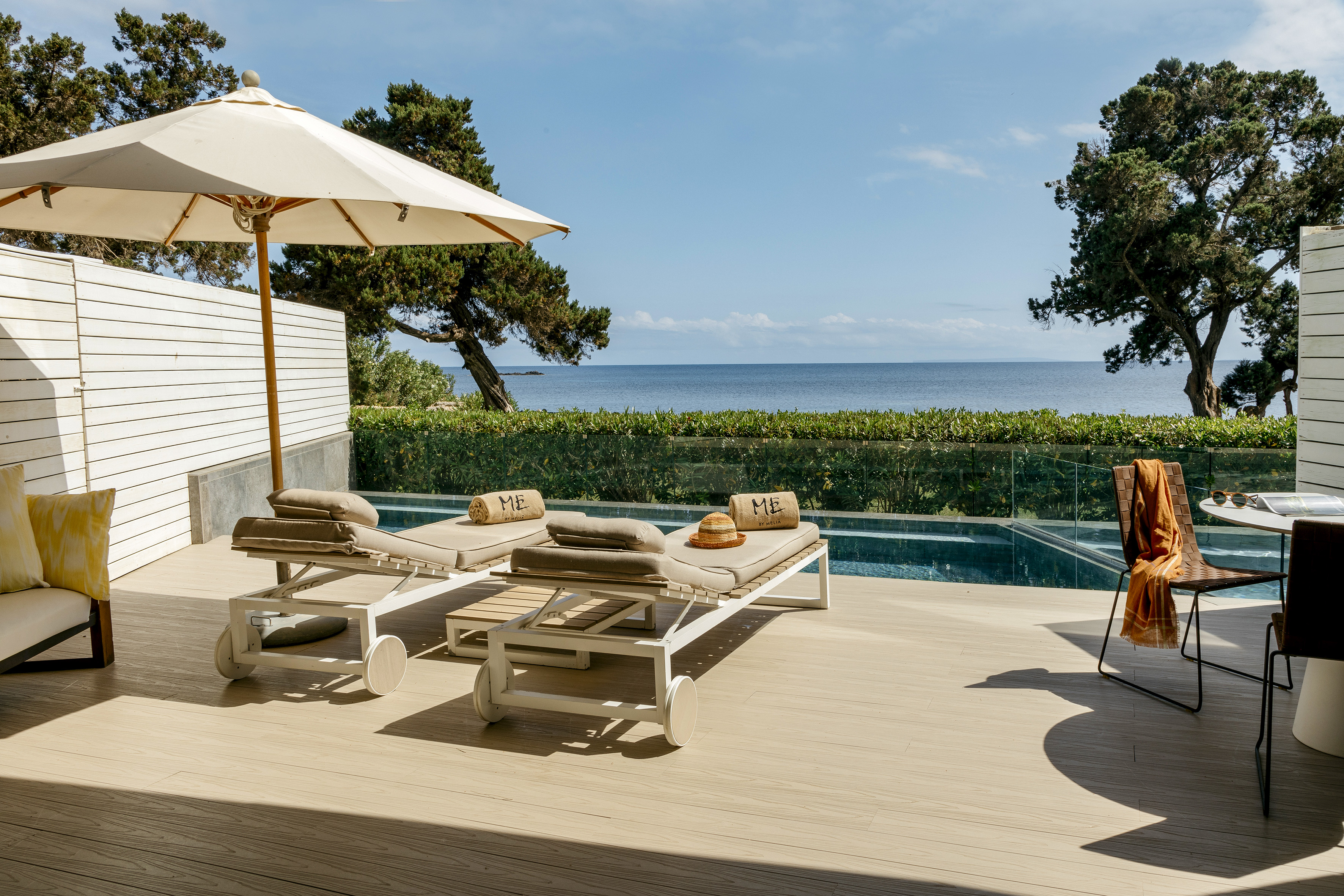 a deck with chairs and umbrellas on a deck overlooking a body of water