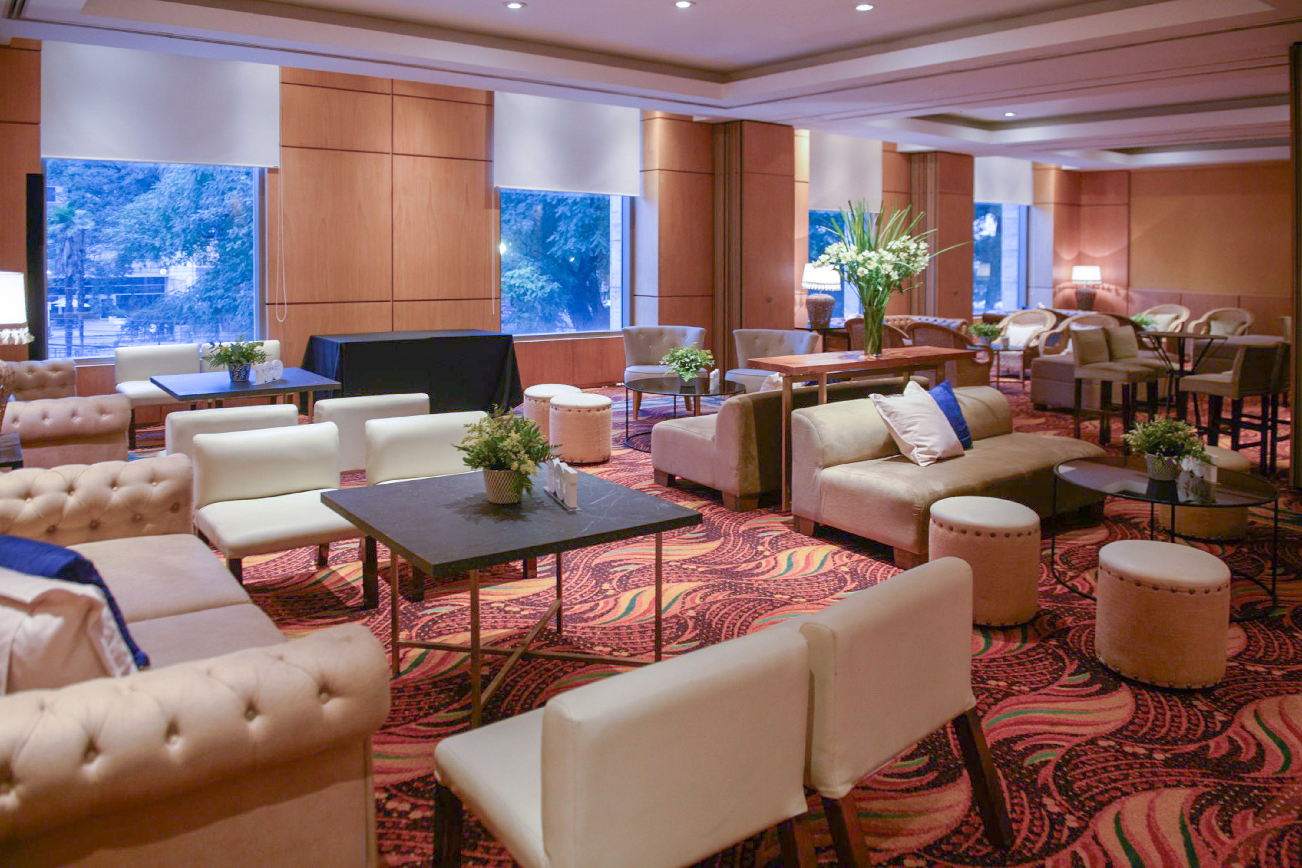 Modern lounge with comfortable seating, patterned carpet, and large windows.