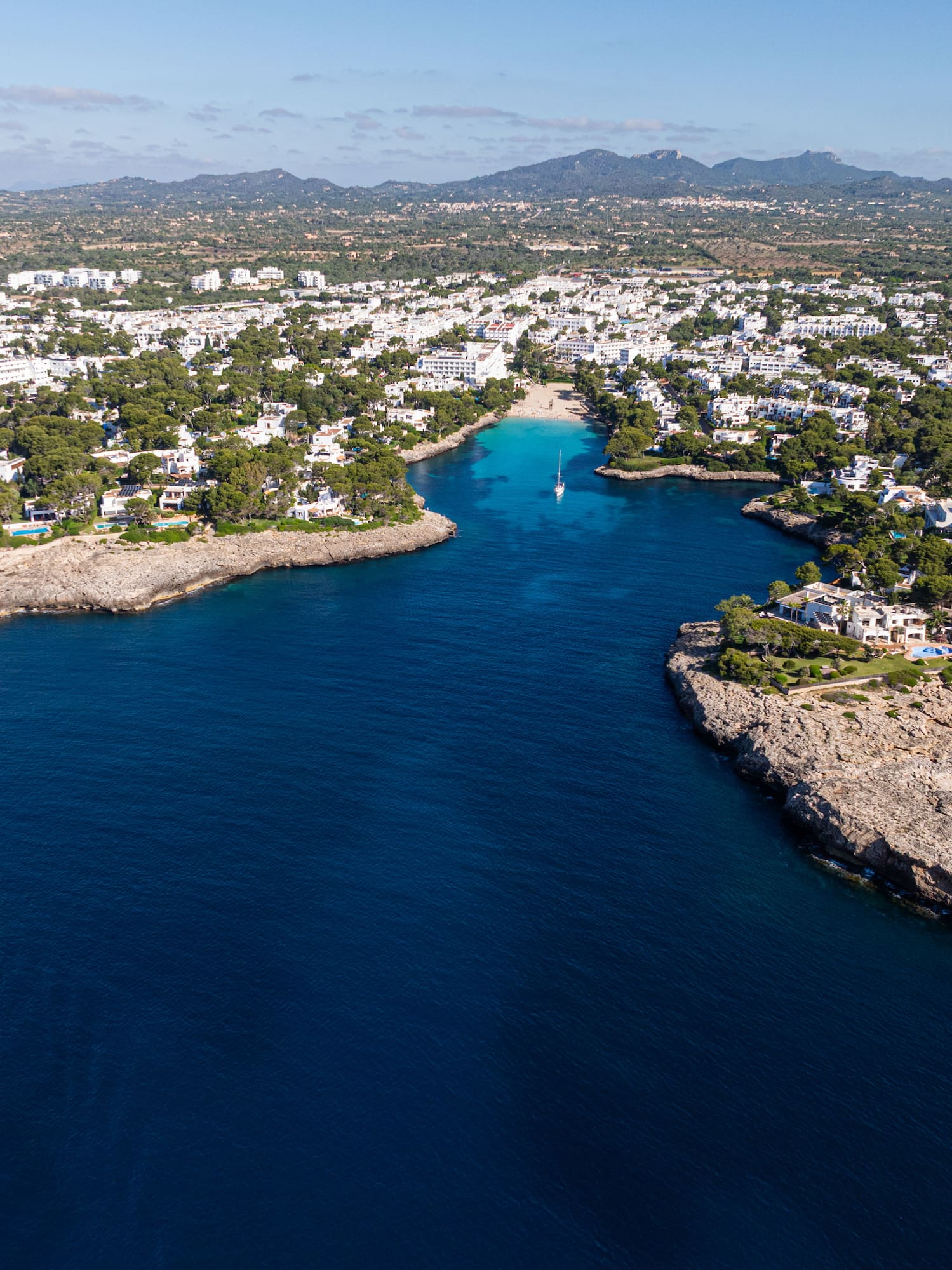 Pueblo costero en Mallorca con cala de aguas turquesas y villas blancas.