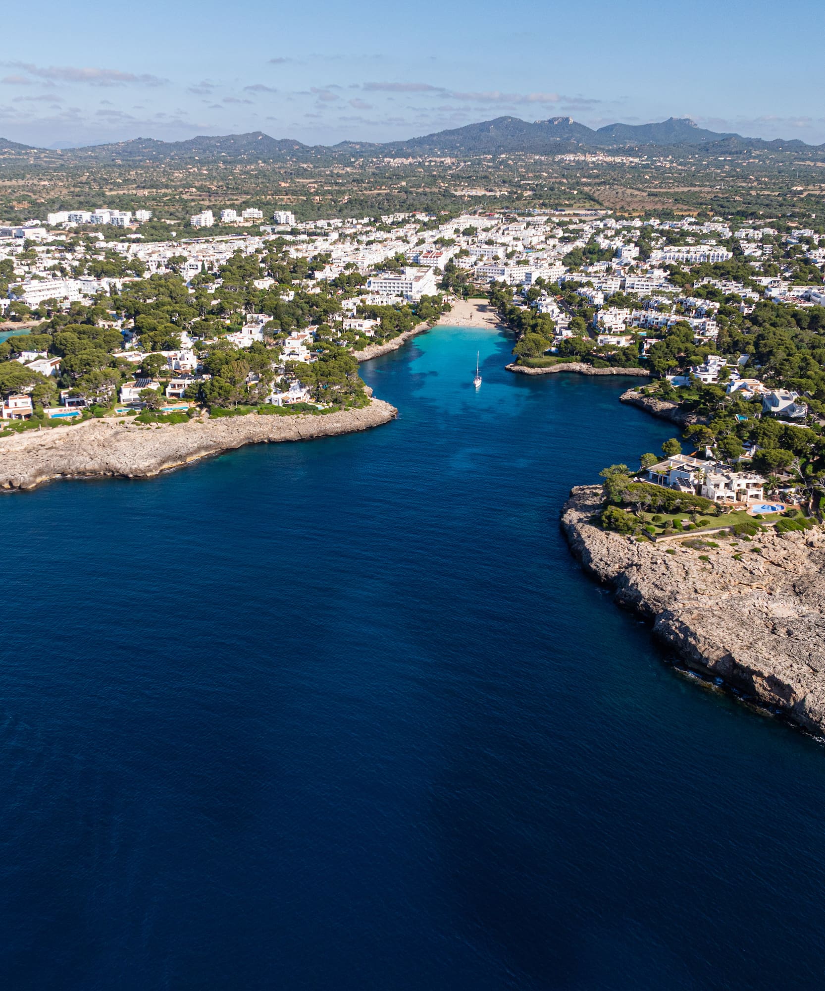 Pueblo costero en Mallorca con cala de aguas turquesas y villas blancas.