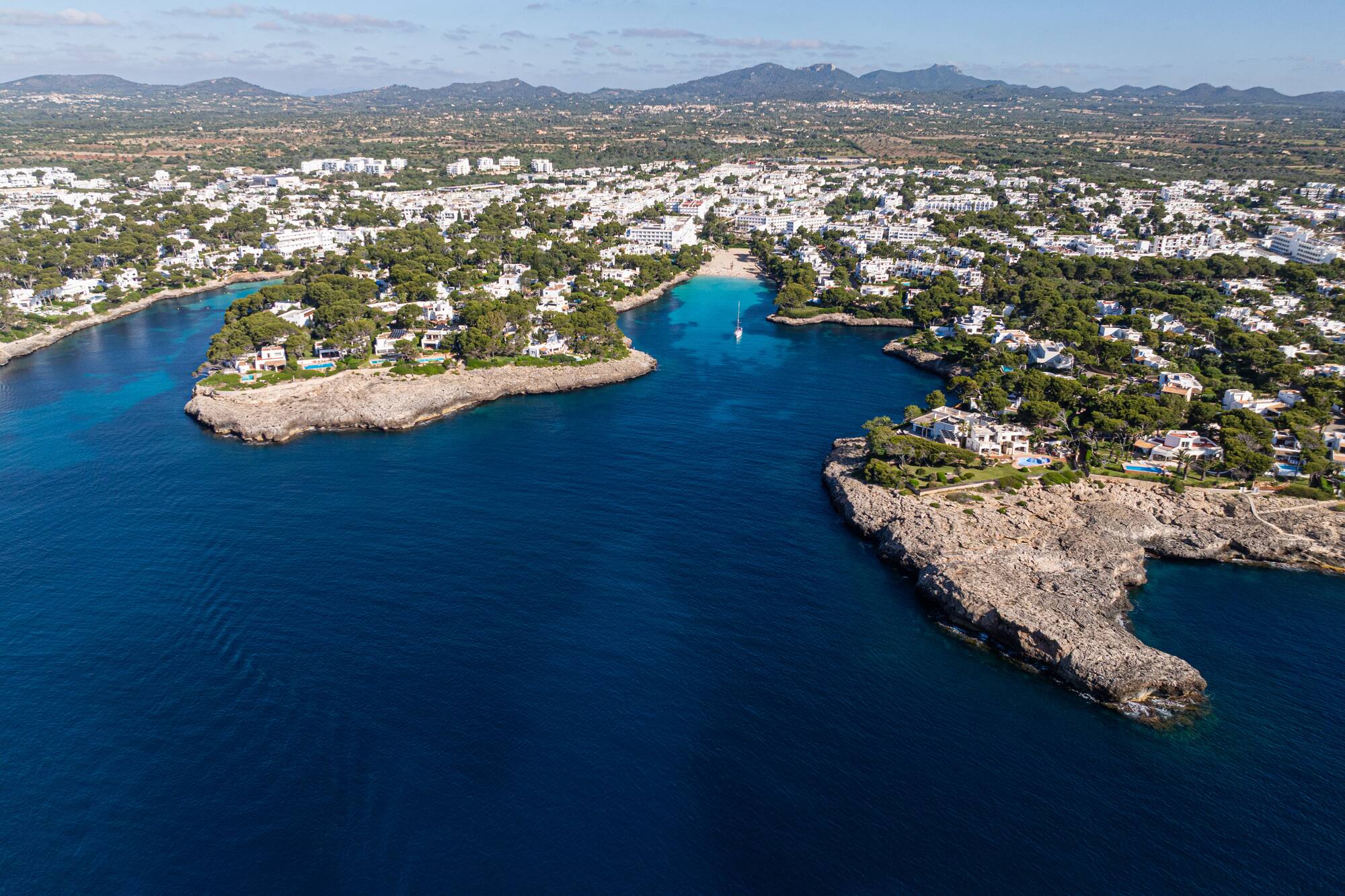 Pueblo costero en Mallorca con cala de aguas turquesas y villas blancas.