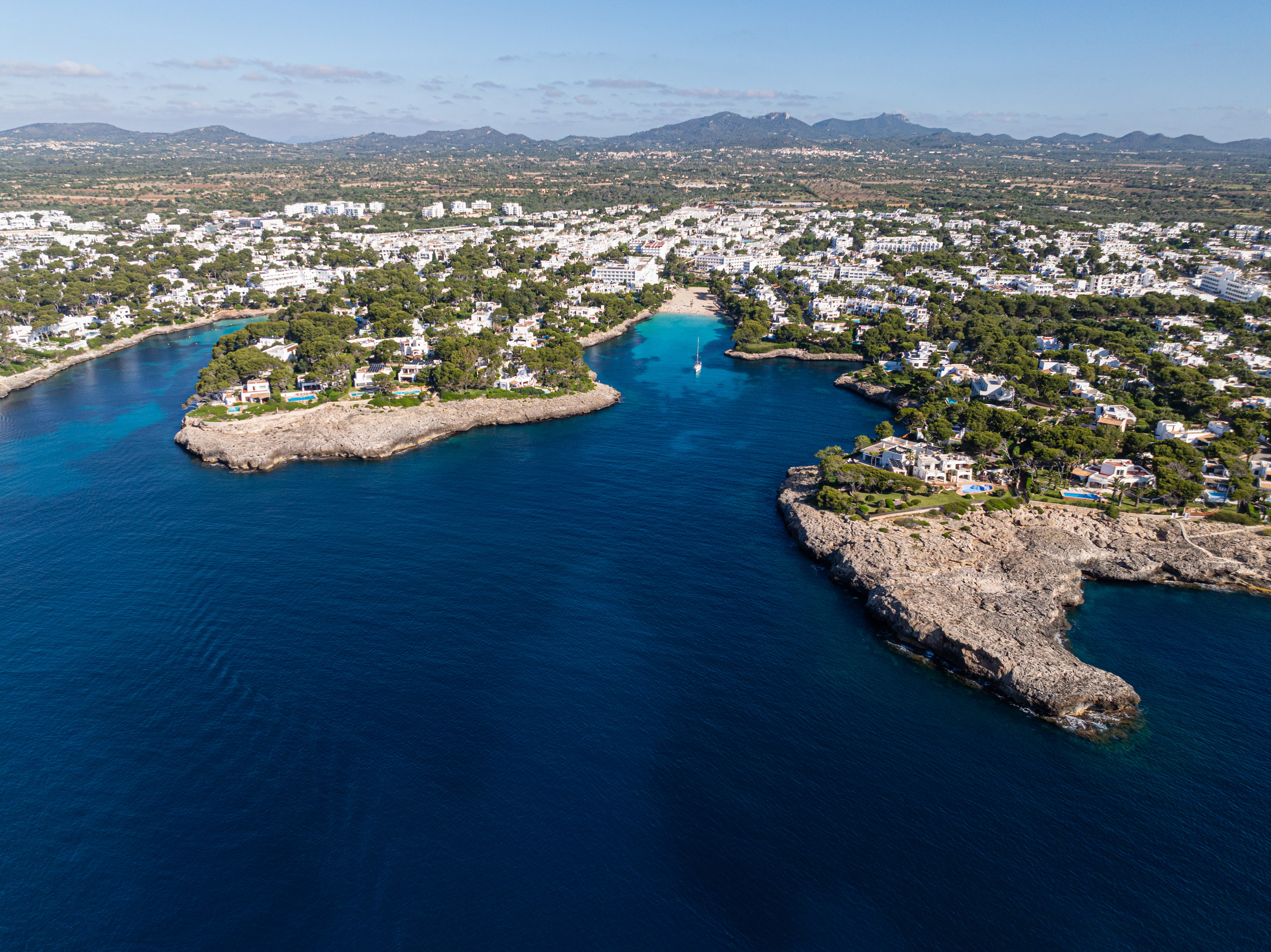 Pueblo costero en Mallorca con cala de aguas turquesas y villas blancas.