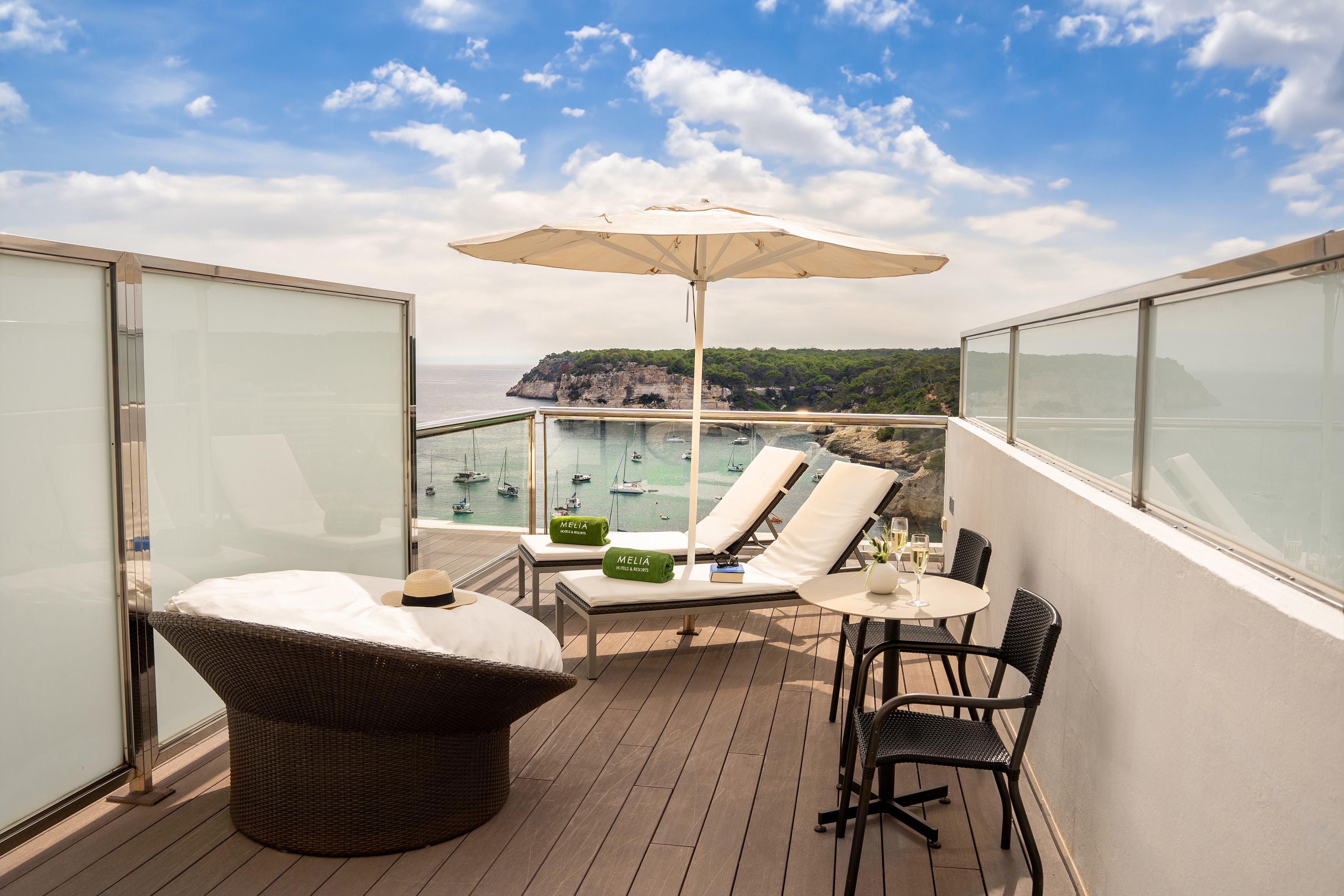 Meliá hotel balcony overlooking a bay with boats, sun loungers, and umbrella.