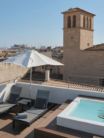 a deck with chairs and a pool on a rooftop