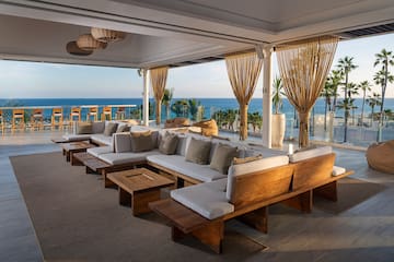 a large couches and tables in a room with a view of the ocean